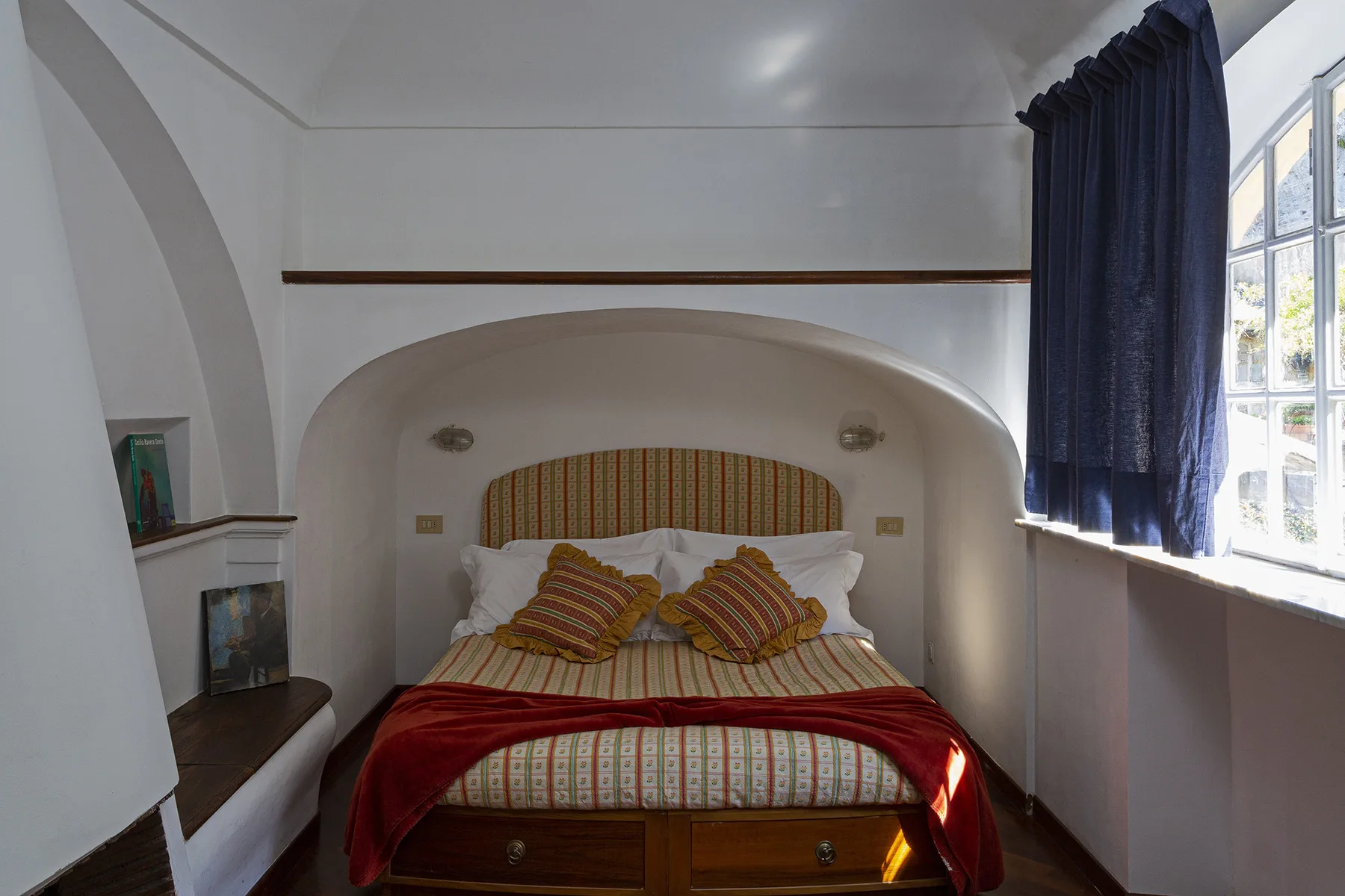 Un dormitorio con una cama de ropa de cama estampada bajo un arco.