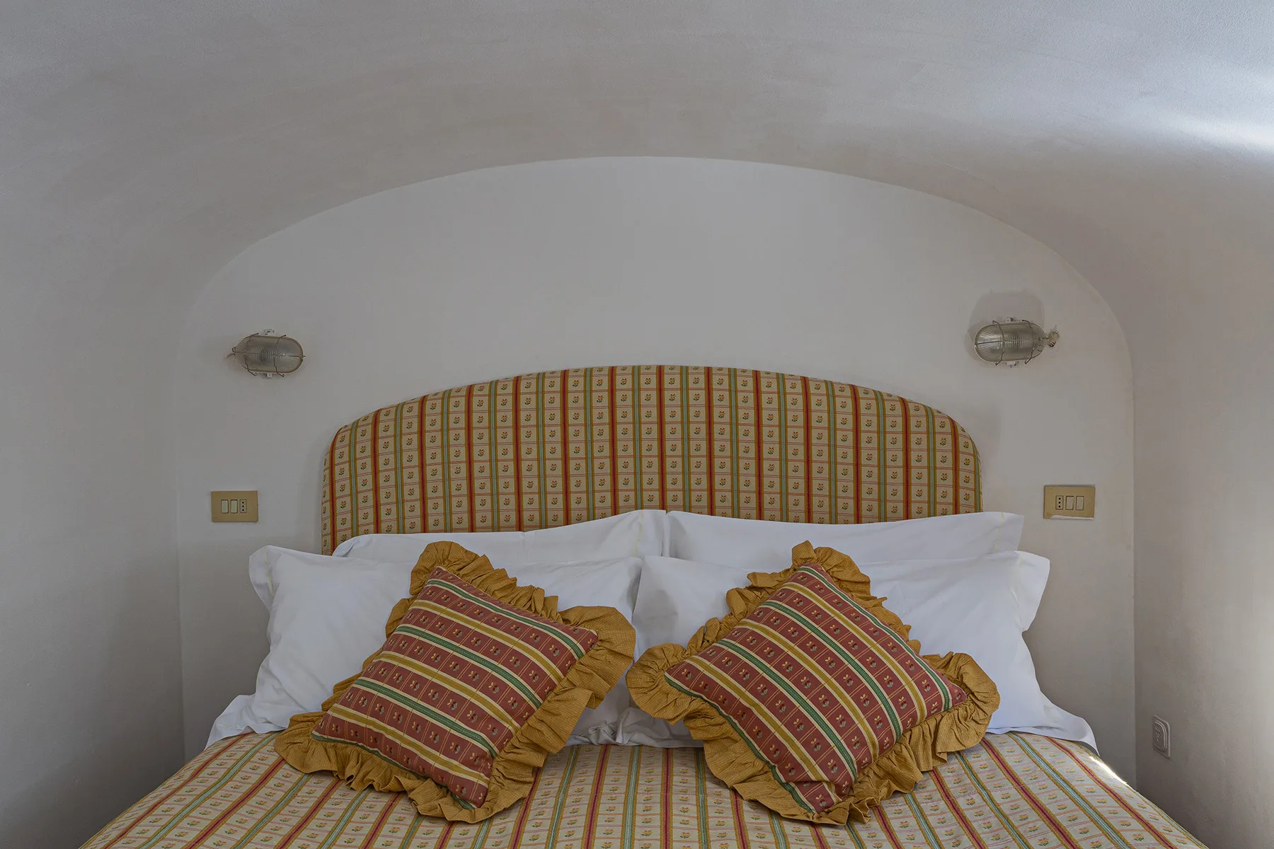 A bedroom with a bed dressed in patterned bedding and decorative pillows.
