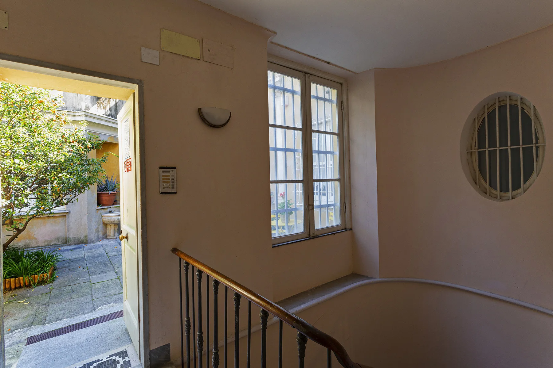 A stairwell landing with tall windows and a doorway opening onto a courtyard.