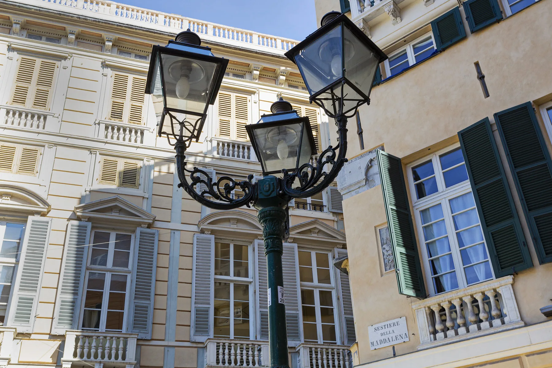 An ornate street lamp stands in front of buildings with shuttered windows.