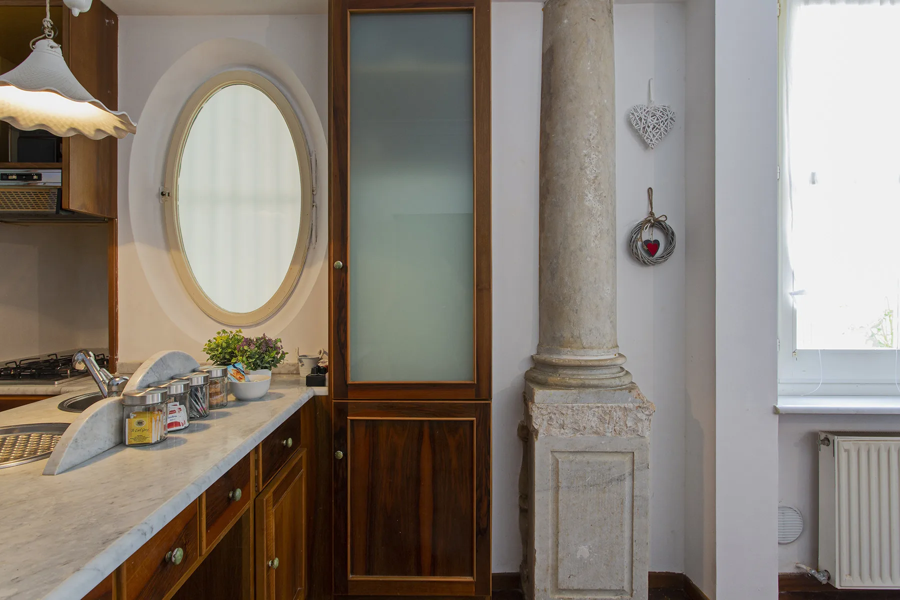 A kitchen counter sits beside an oval window and a wooden door.