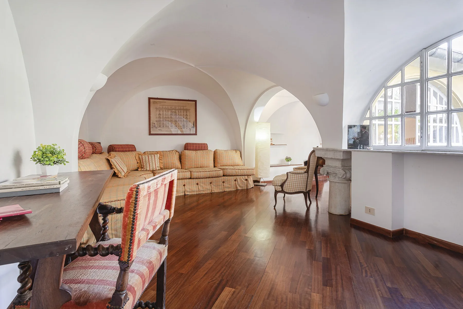 Una sala luminosa con arcos curvos, asientos estampados y una gran ventana arqueada.