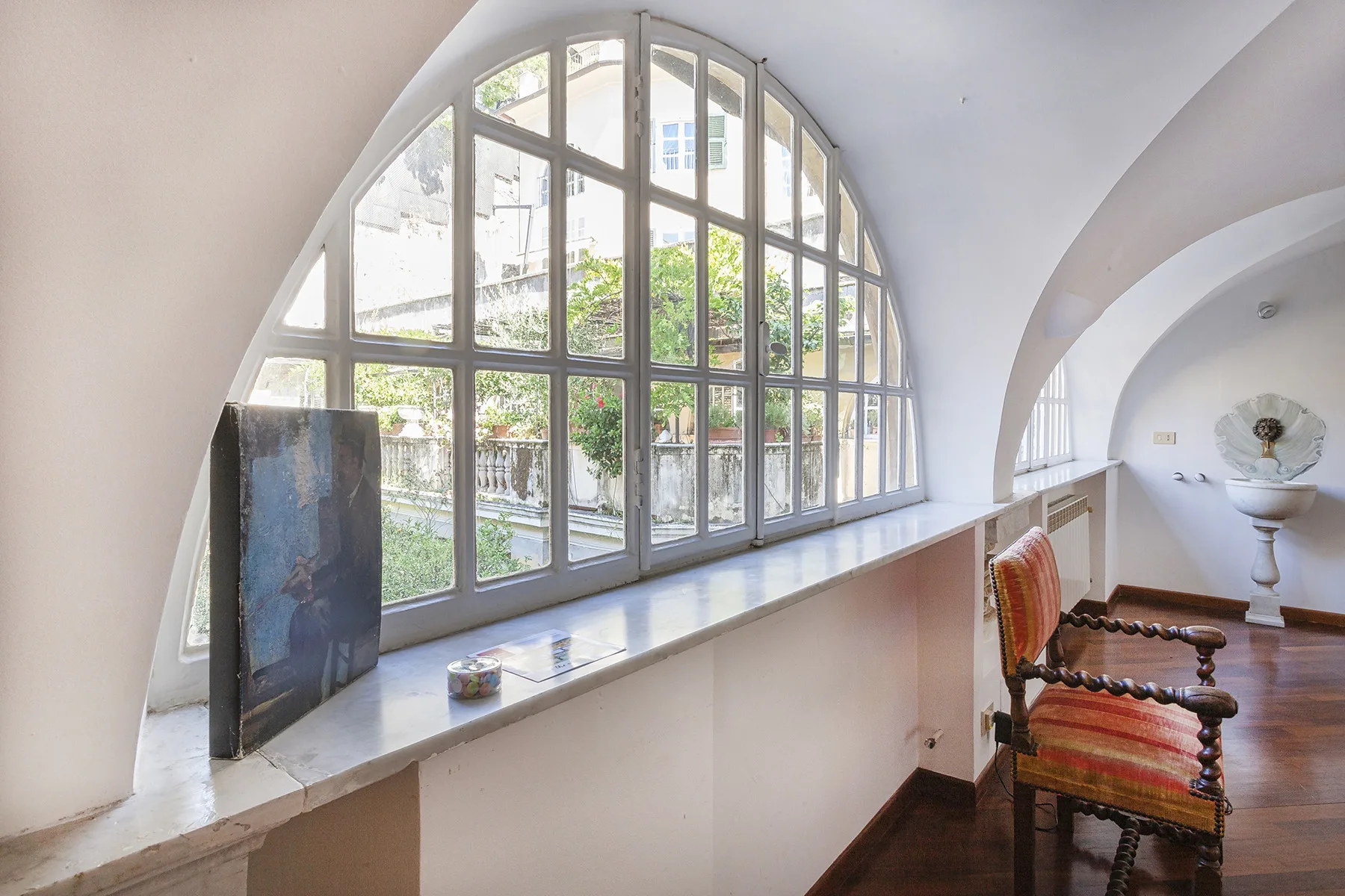 A bright room with a large arched window and a chair beside it.