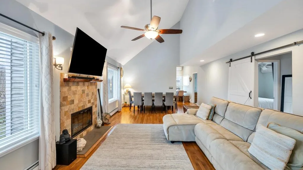 A bright living room with a sectional seating area and dining space beyond.