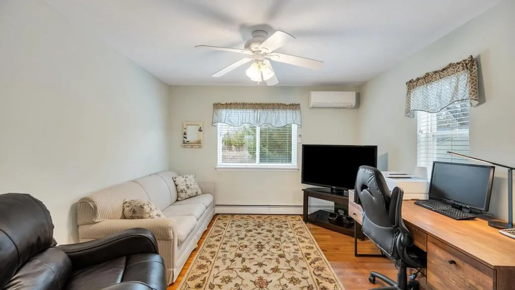 A living room with a sofa, television, and desk.