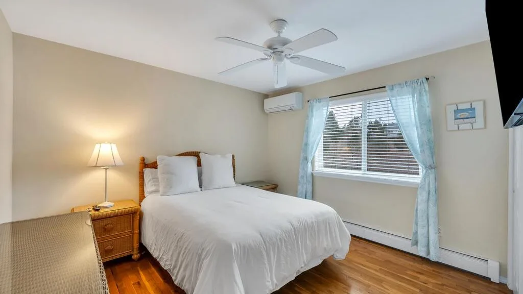 A bedroom with a bed, bedside table, and window with blue curtains.