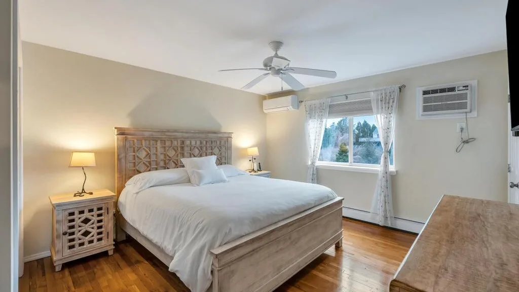 A bedroom with a bed, bedside tables, and a window with curtains.