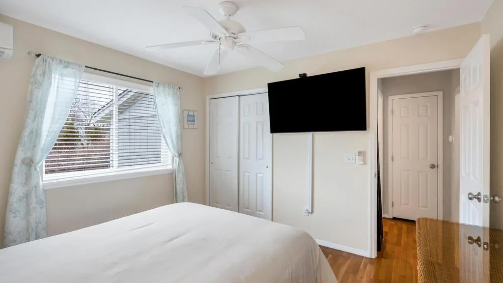 A bedroom with a bed, window, and wall-mounted television.