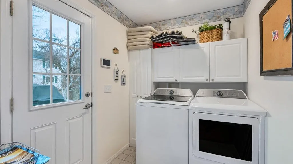 Laundry room with a washer and dryer beneath overhead storage cabinets.