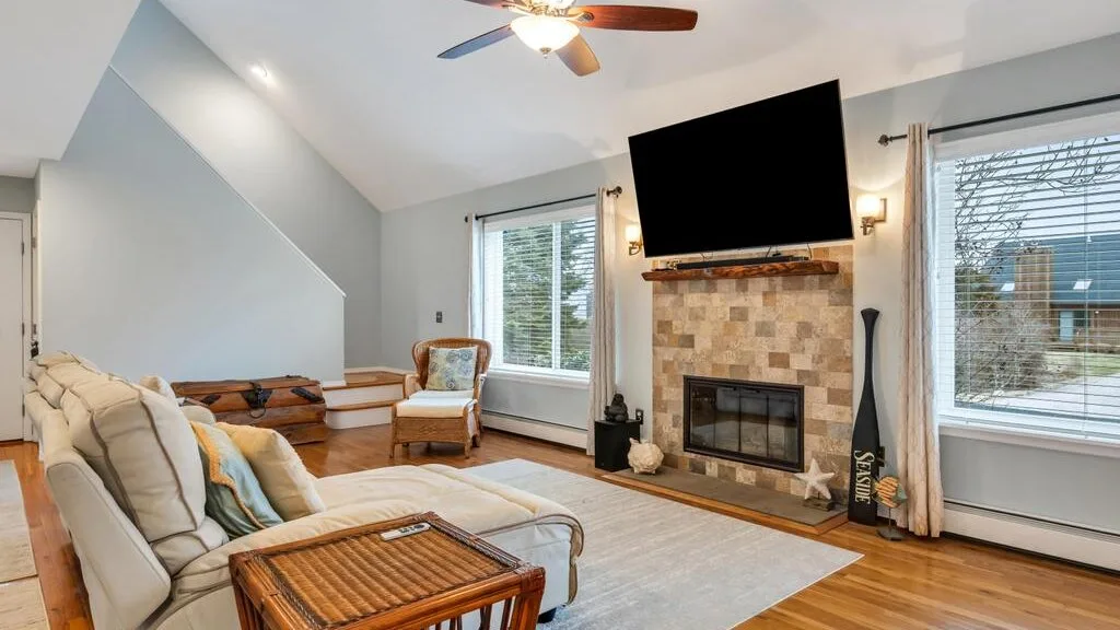 A living room with seating arranged around a fireplace and large television.