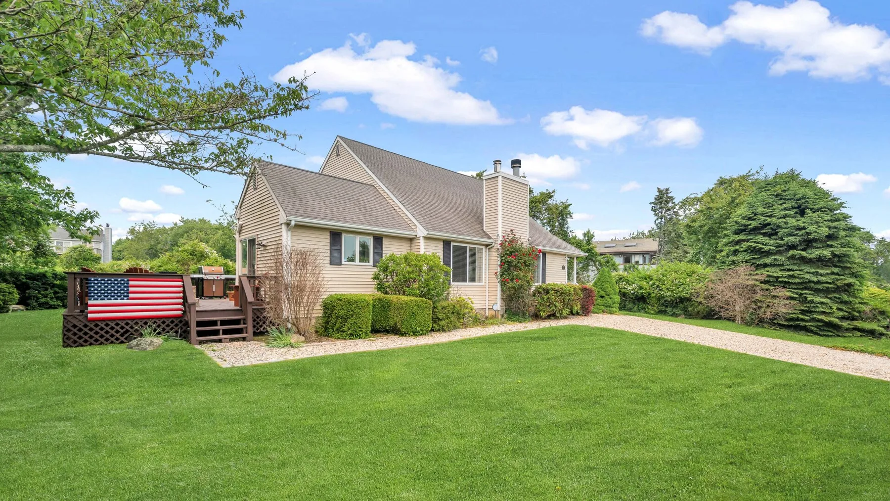 A house with a green lawn, shrubs, and a paved path.