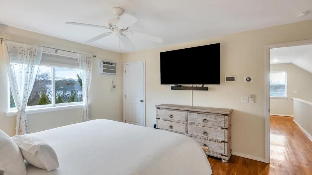 A bedroom with a large bed, a dresser, and a wall-mounted television.