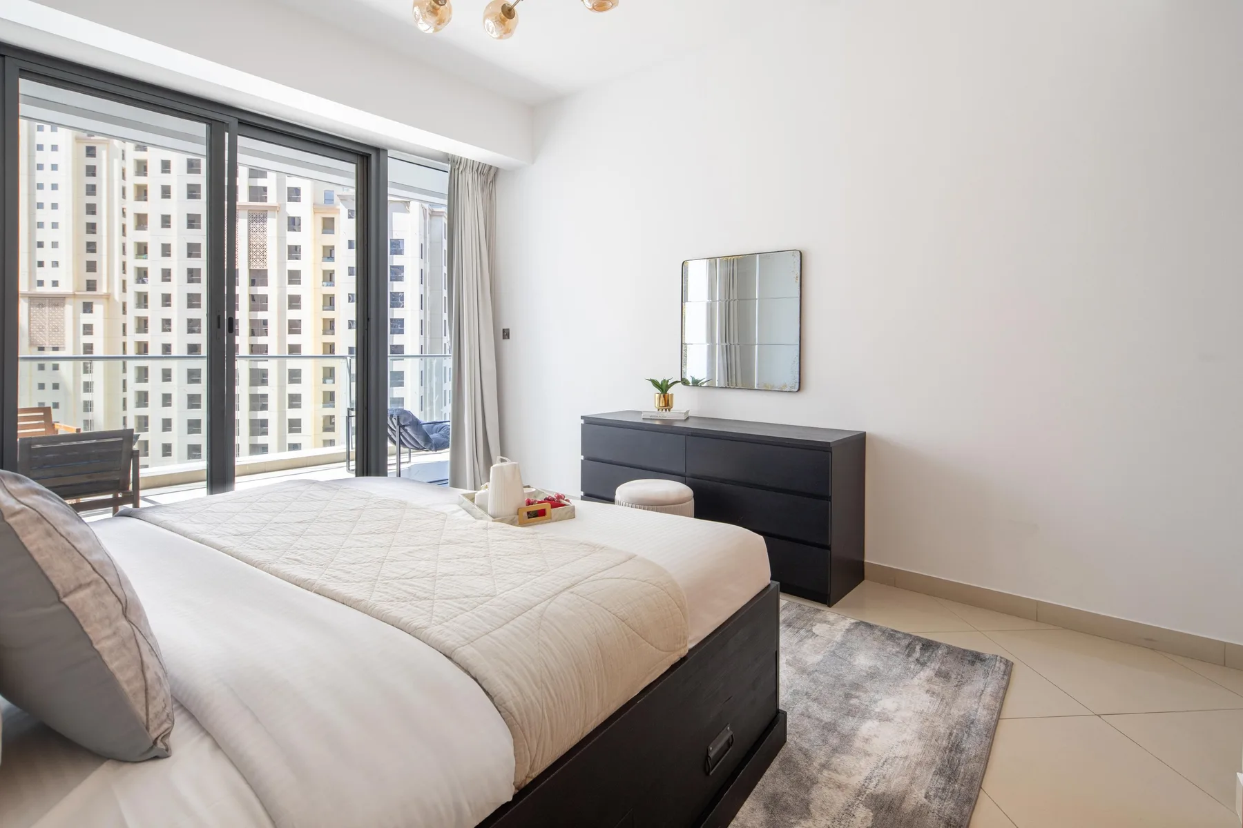 Un dormitorio luminoso con una cama grande junto a puertas corredizas de vidrio.