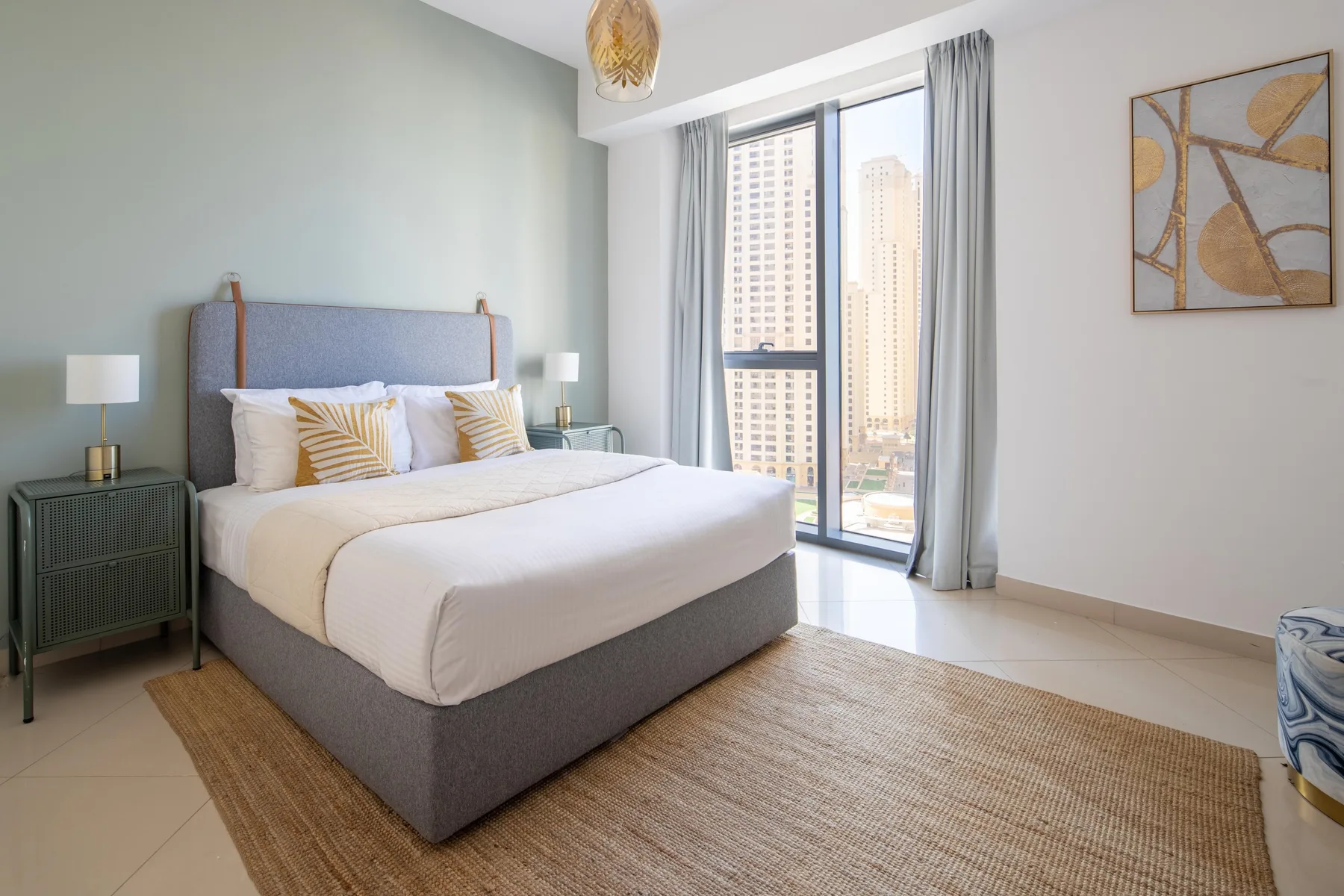 Un dormitorio con una cama bien arreglada junto a una ventana grande.