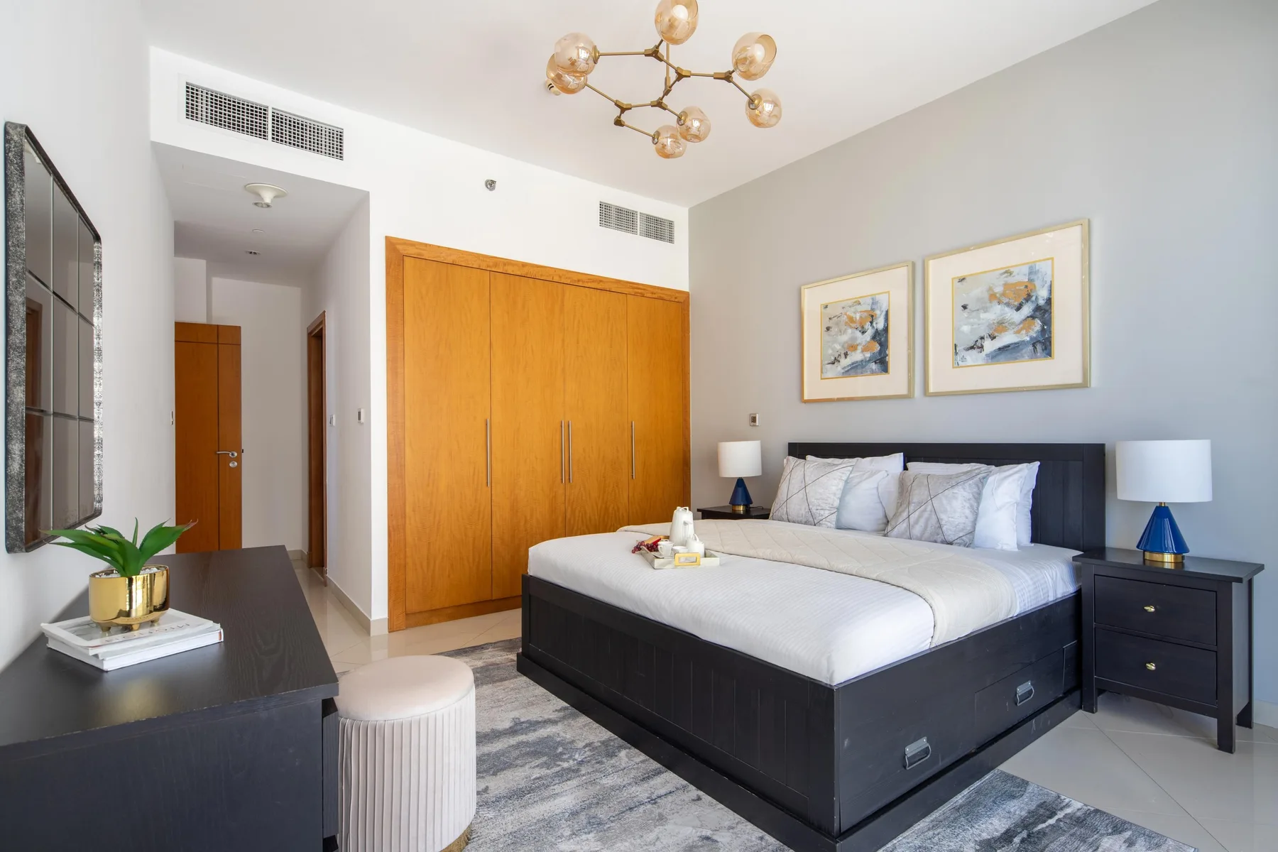 Un dormitorio con una cama grande, puertas de armario de madera y cuadros enmarcados.
