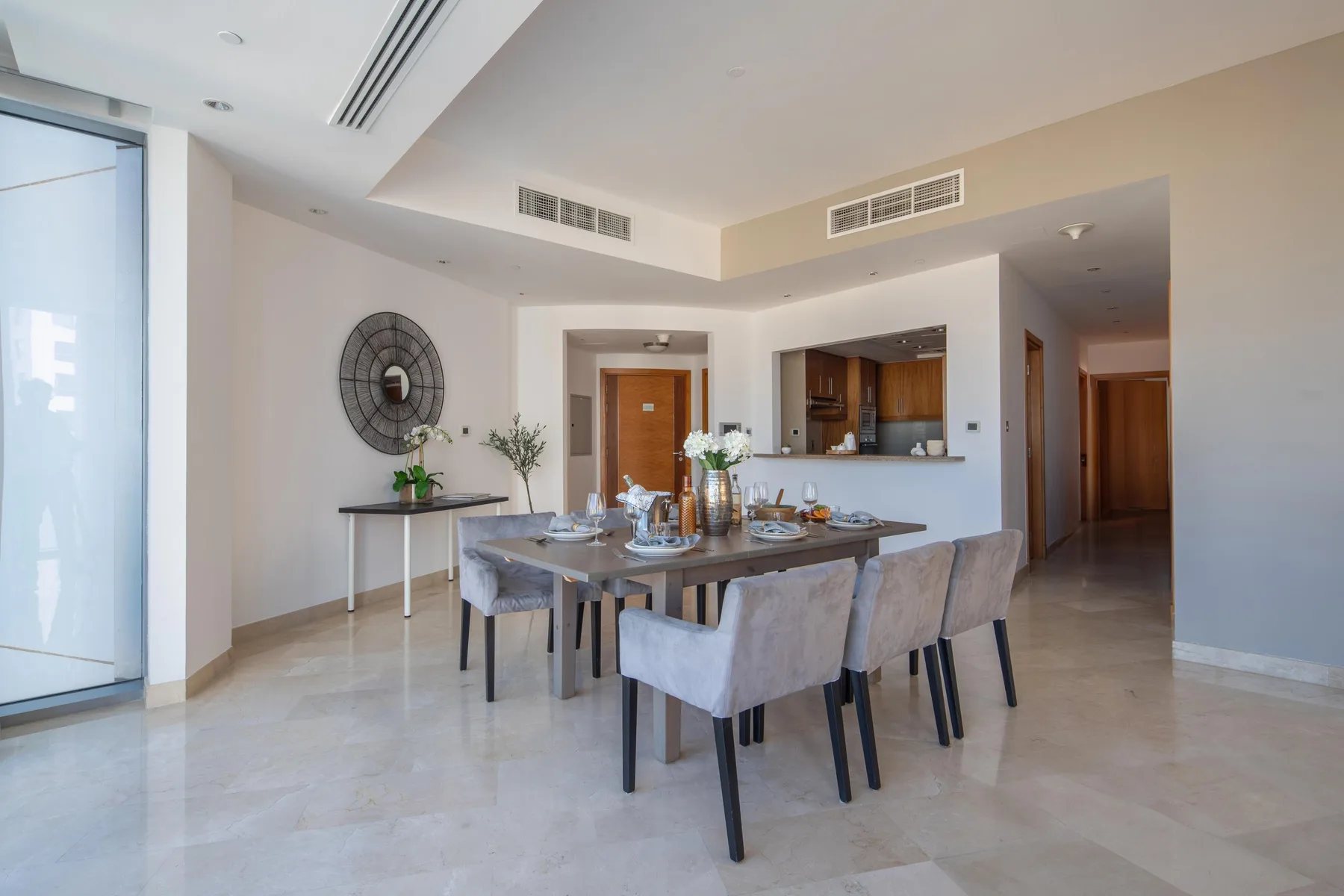 Un comedor con una mesa y asientos tapizados, junto a una cocina abierta.
