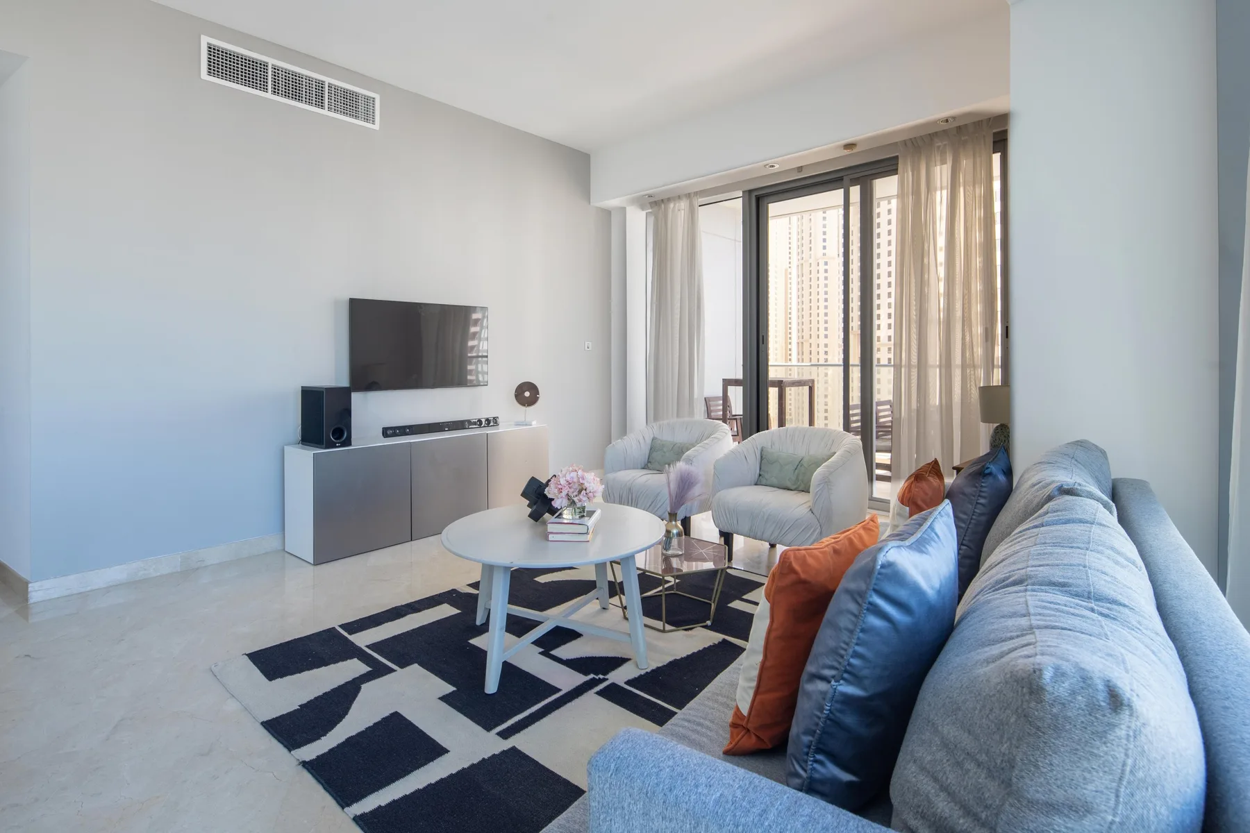 Una sala luminosa con asientos alrededor de una mesa de centro y un televisor.