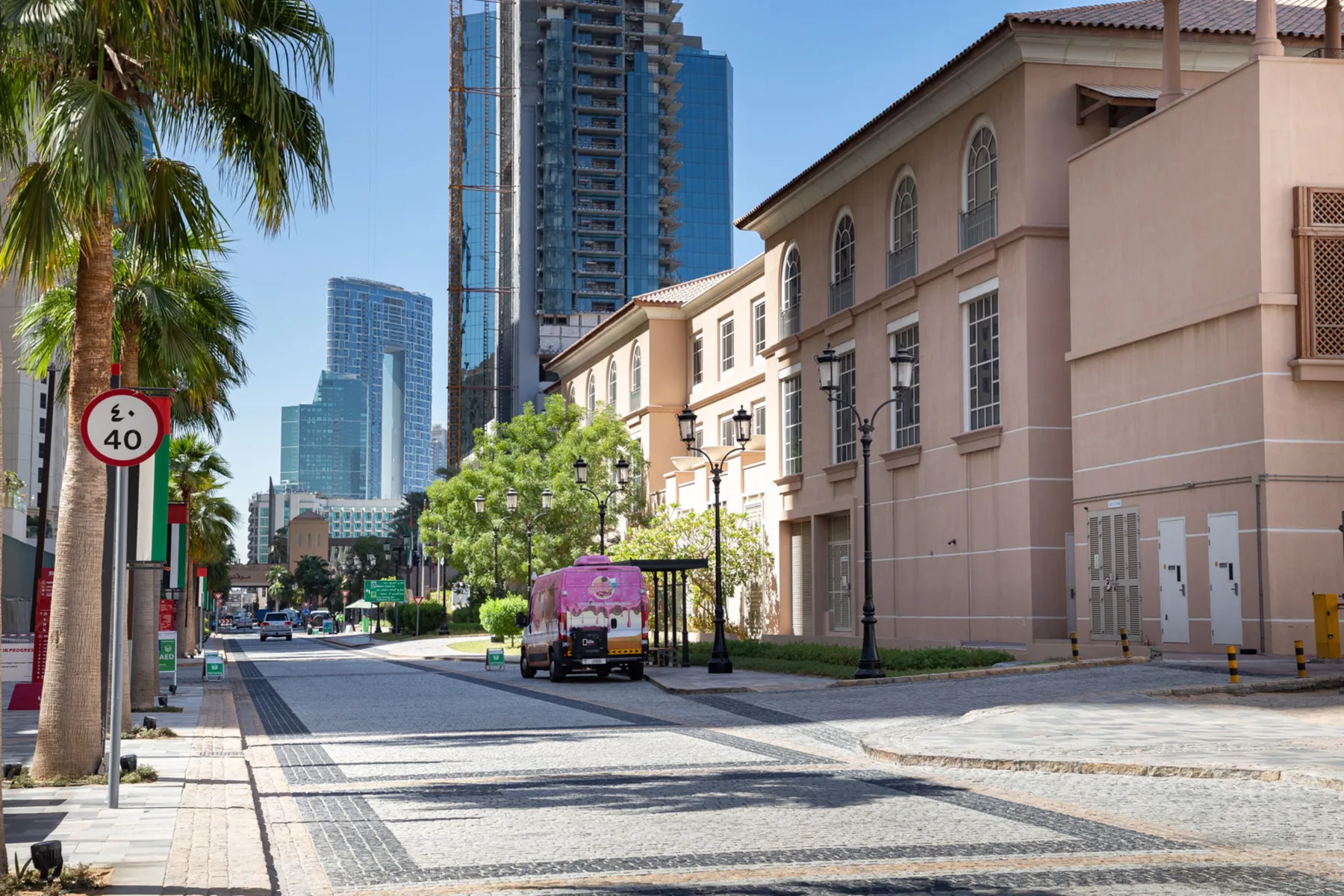 Una calle urbana con edificios, palmeras y rascacielos modernos.