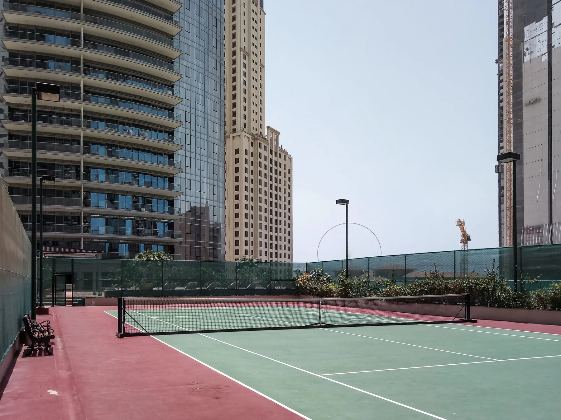 Una cancha de tenis al aire libre está rodeada de edificios altos.
