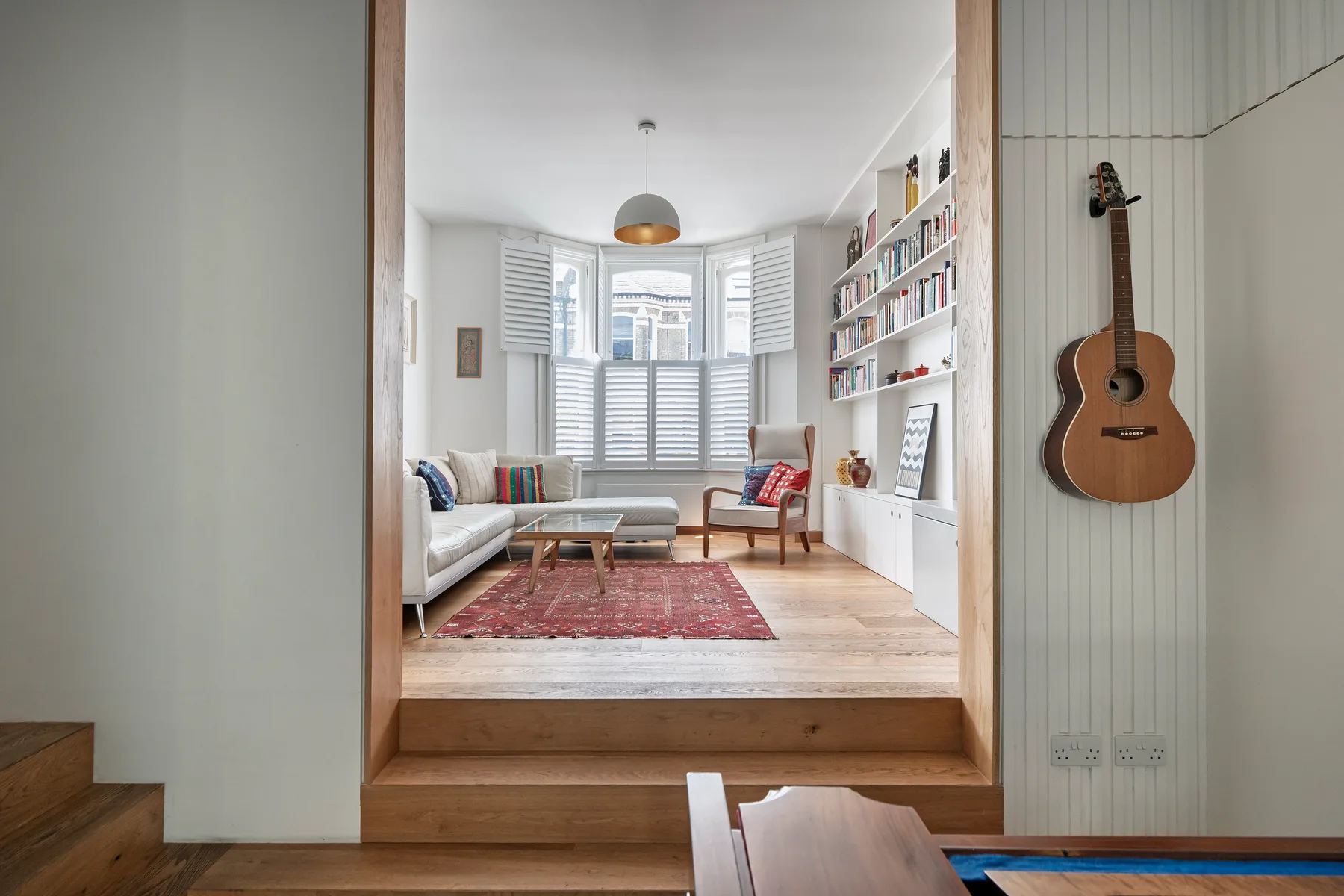 Una sala luminosa con ventana salediza, asientos y estanterías empotradas.