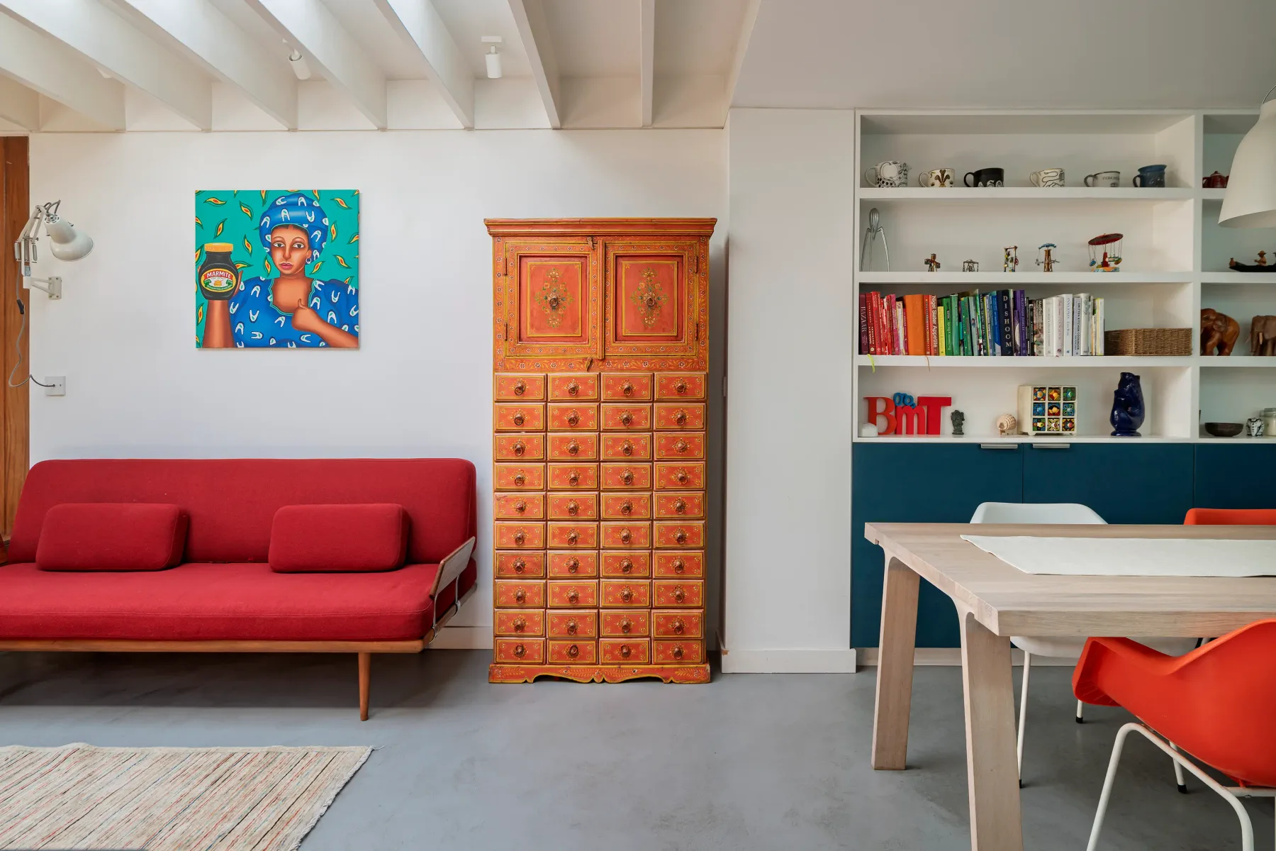 Sala de estar y comedor con un sofá rojo y estanterías empotradas.