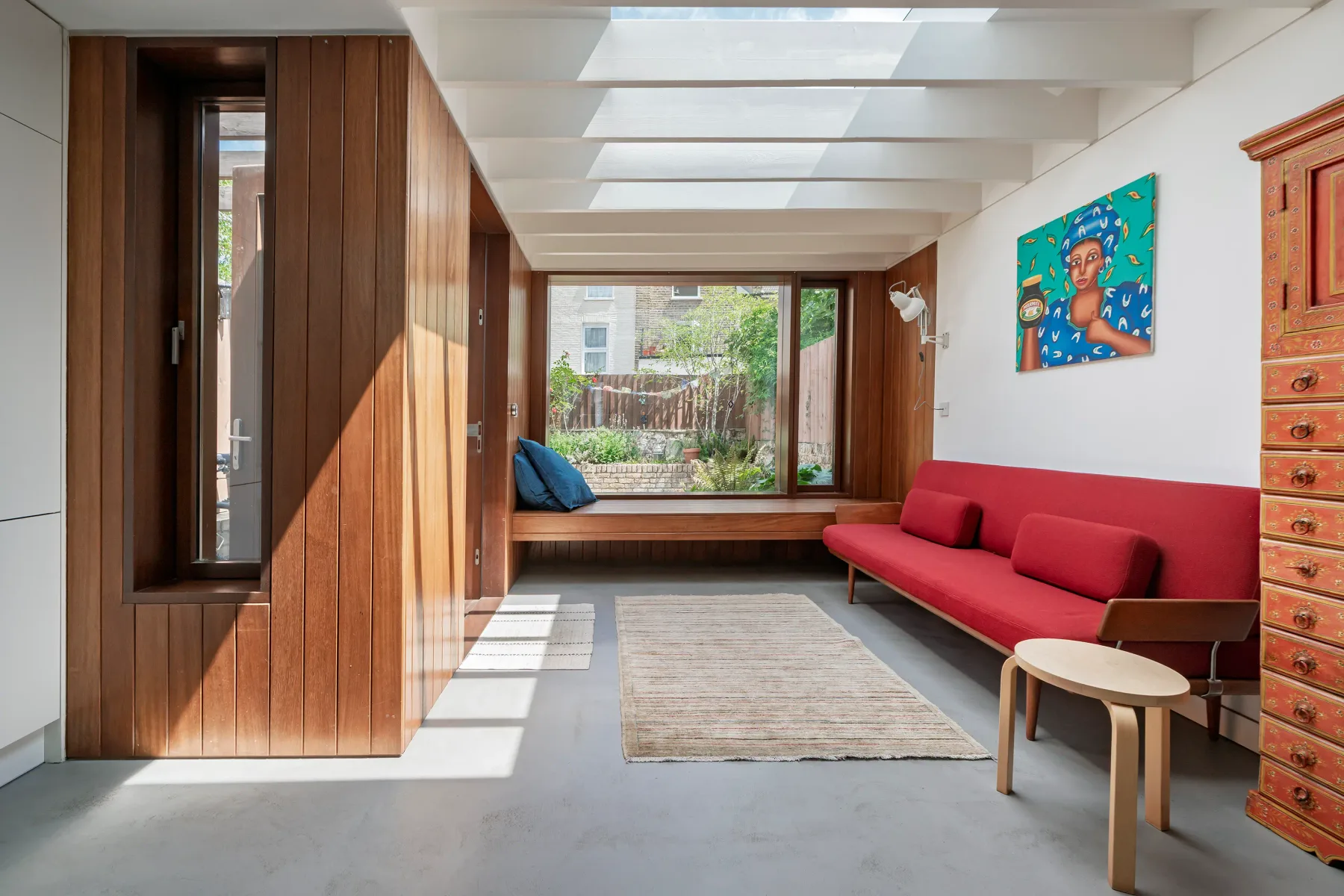 Una sala de estar luminosa con un sofá rojo y una ventana grande.