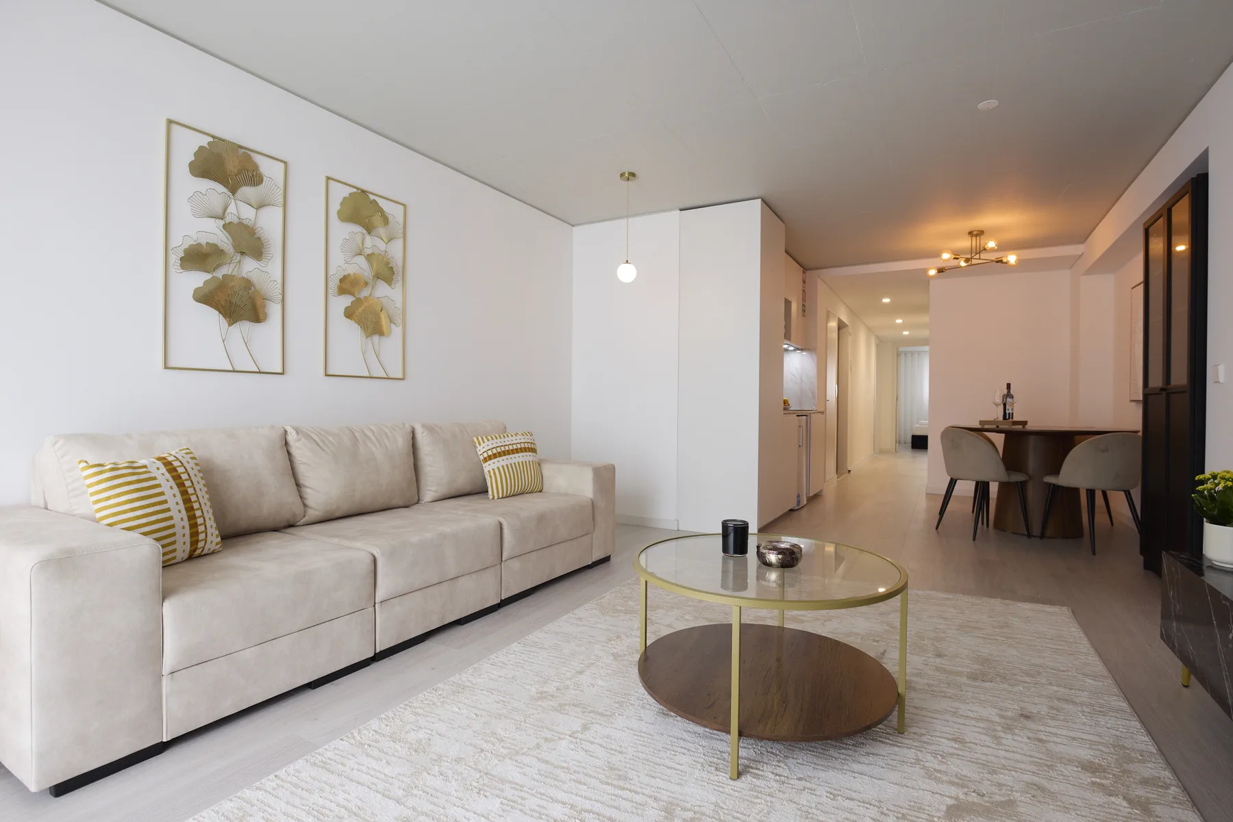 A living room with seating and a round coffee table beside a dining area.