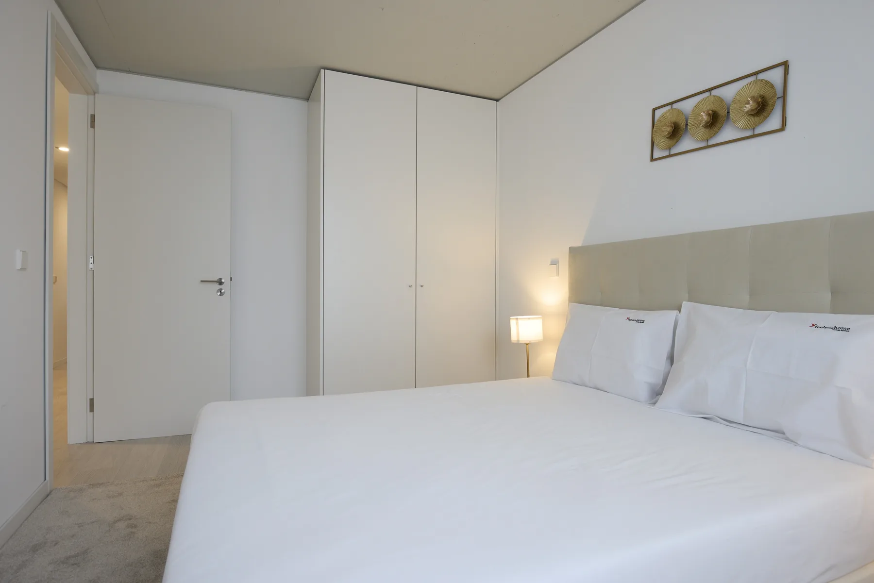 A bedroom with a neatly made bed and a small bedside lamp.