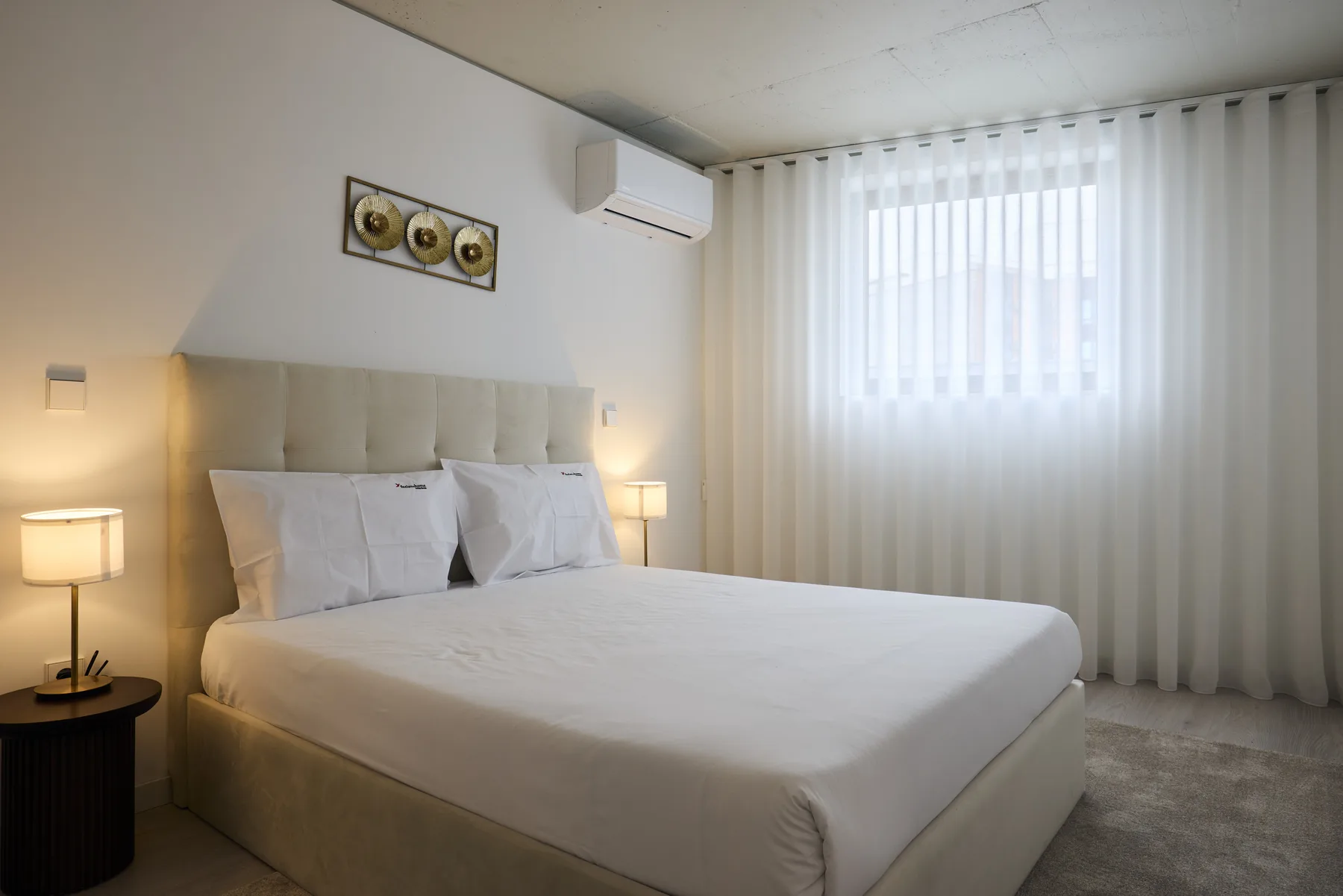 A bedroom with a large bed and a curtained window.
