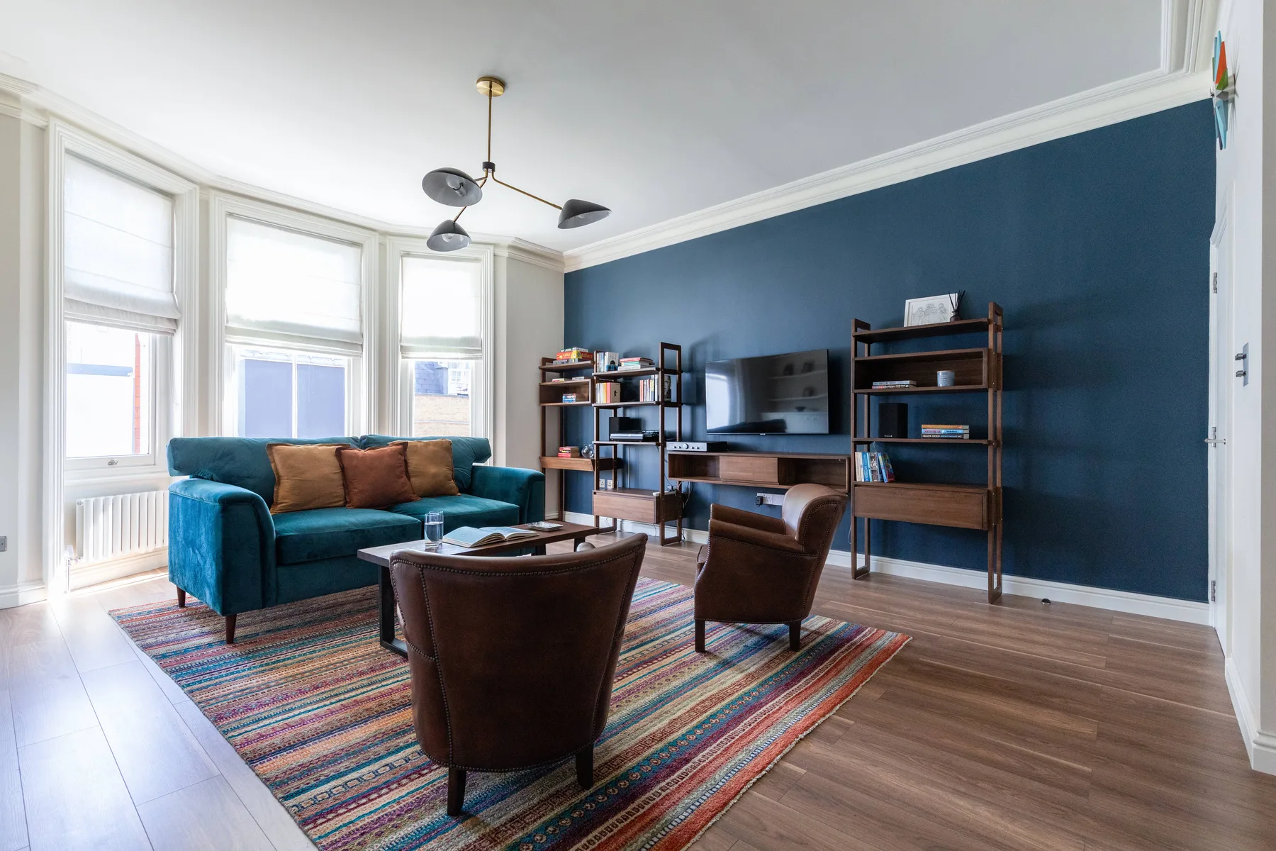 A living room with seating and a television against a dark blue wall.