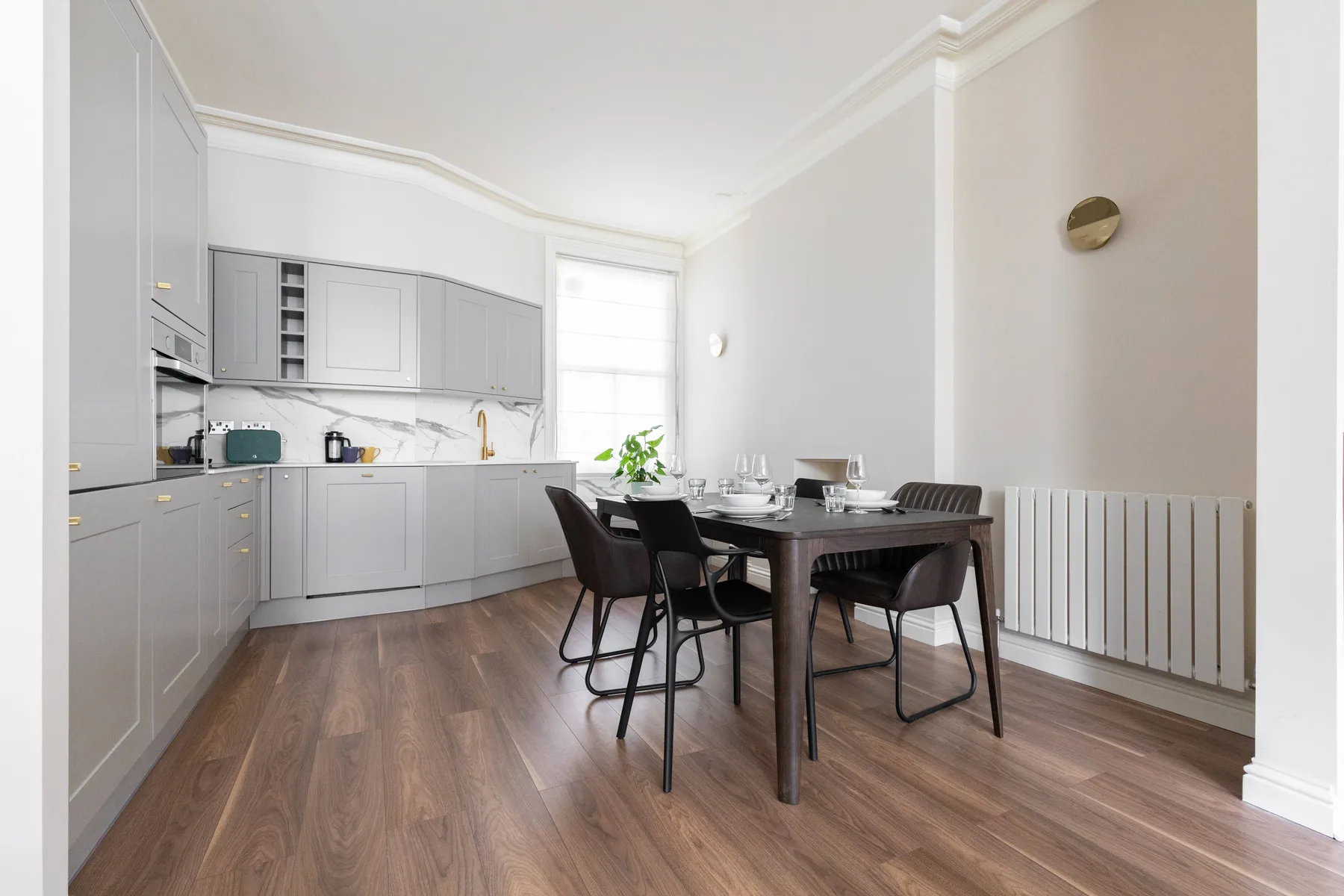 A bright kitchen and dining area with gray cabinetry and a dining table.