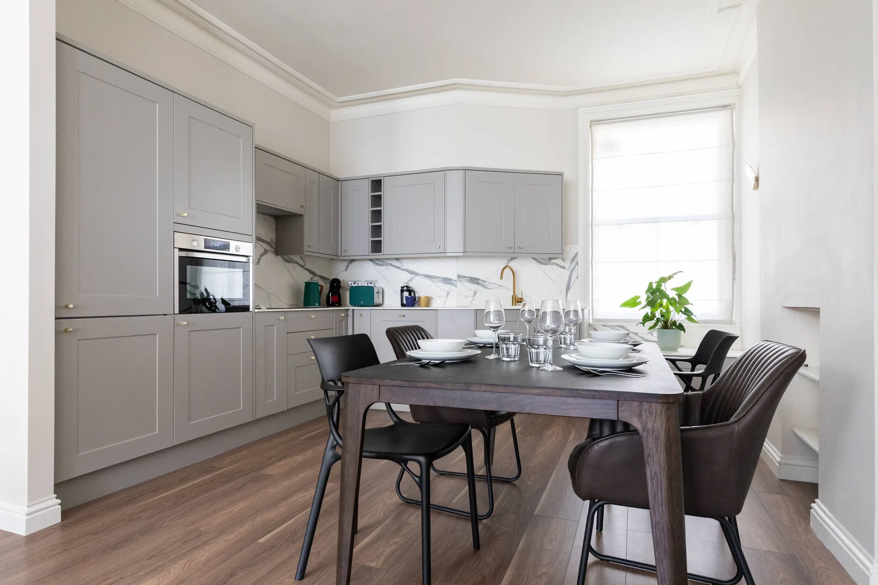 A bright kitchen and dining area with gray cabinetry and a table set with dishes.