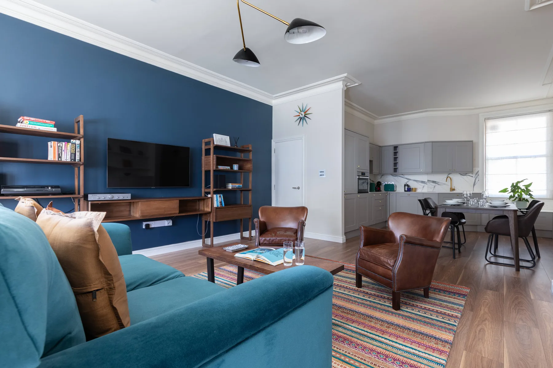 A living room with blue seating and a dining area in the background.