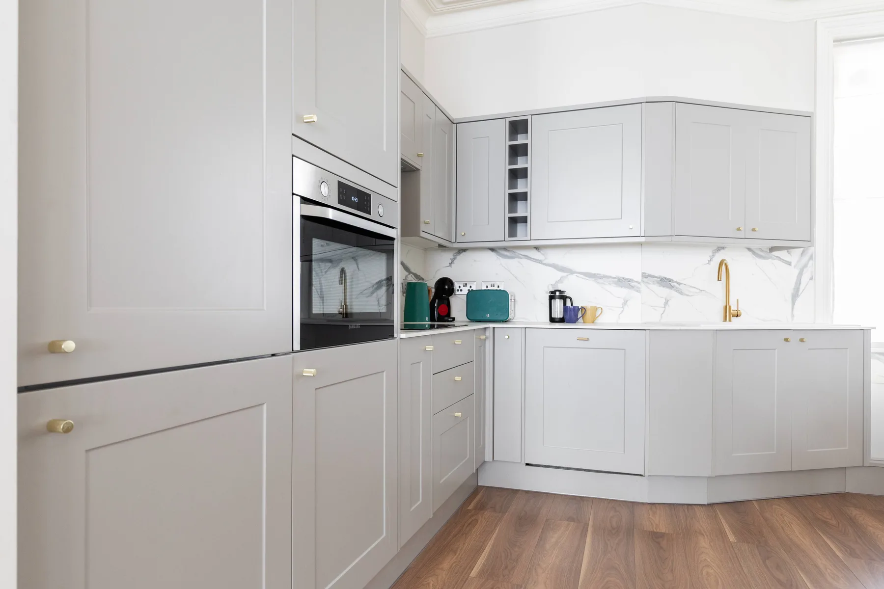 A bright kitchen with light cabinetry, a built-in oven, and a countertop.