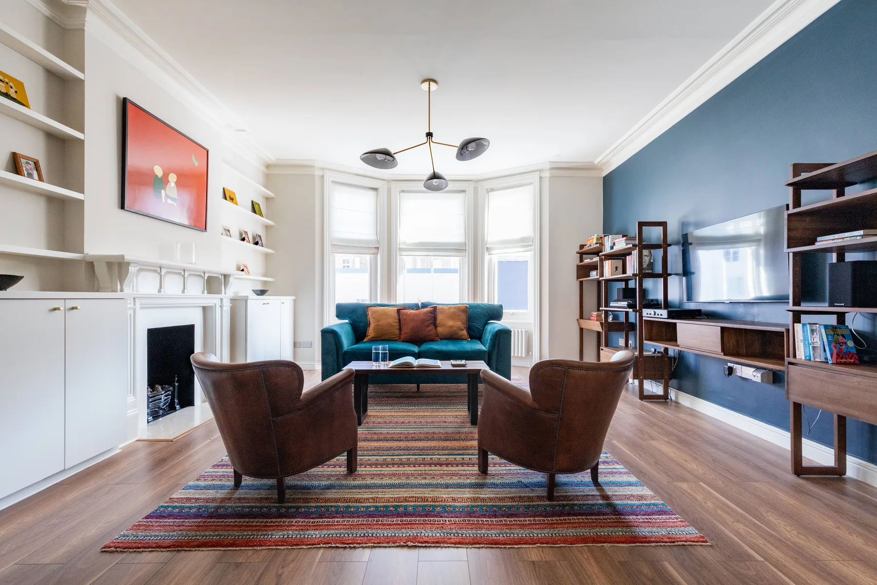 A bright living room with seating arranged around a coffee table and a large television.