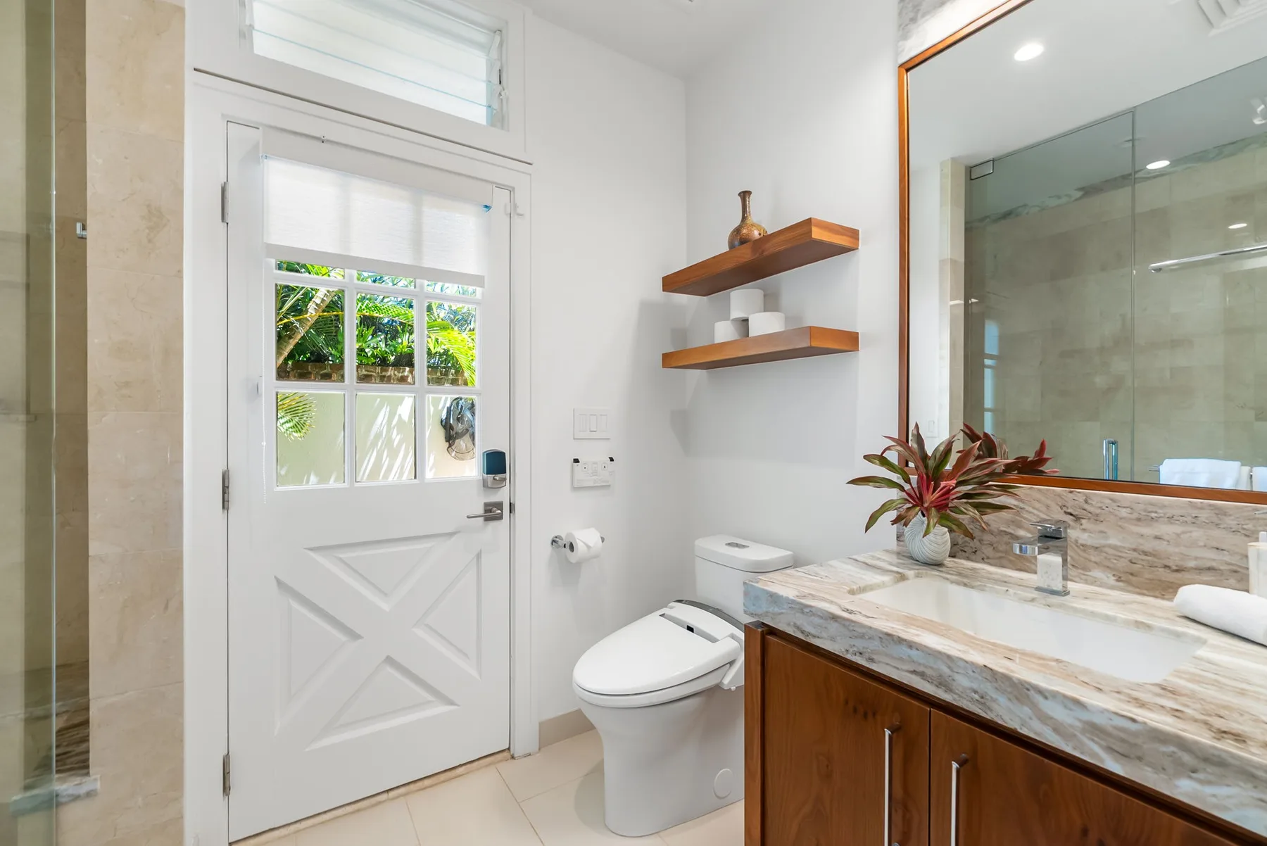 Un baño luminoso con lavabo, inodoro y ducha de vidrio.