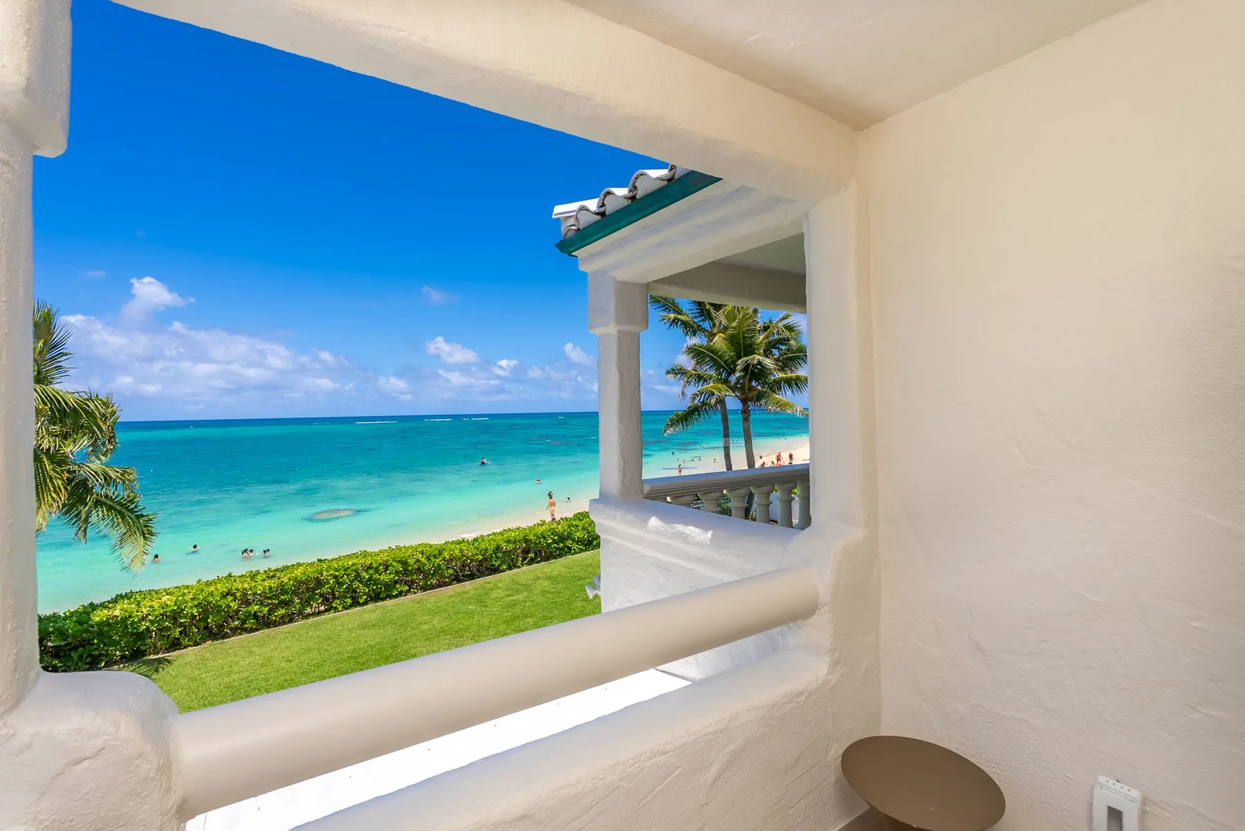 Una habitación de paredes blancas da a una playa tropical y al mar turquesa.