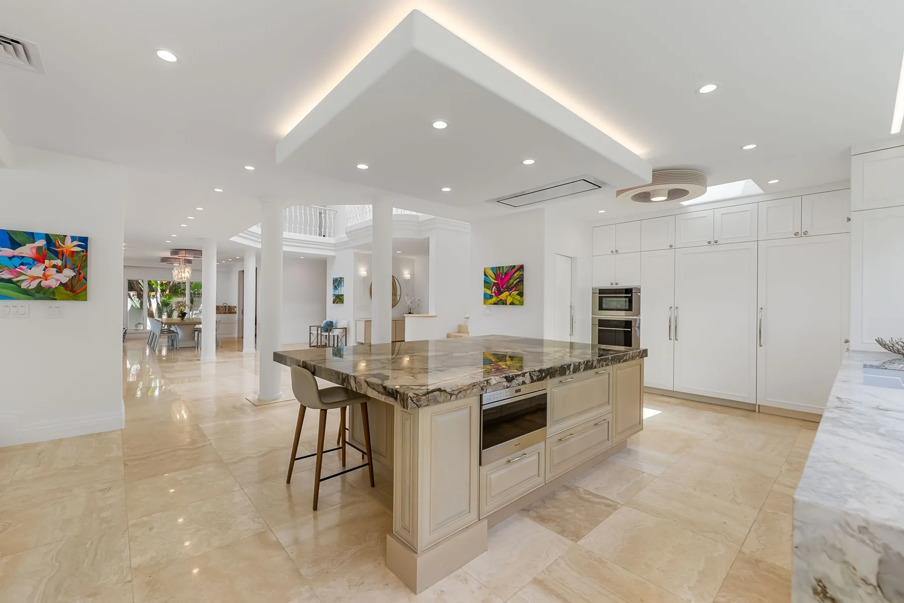 Una cocina luminosa con una gran isla central y gabinetes blancos.