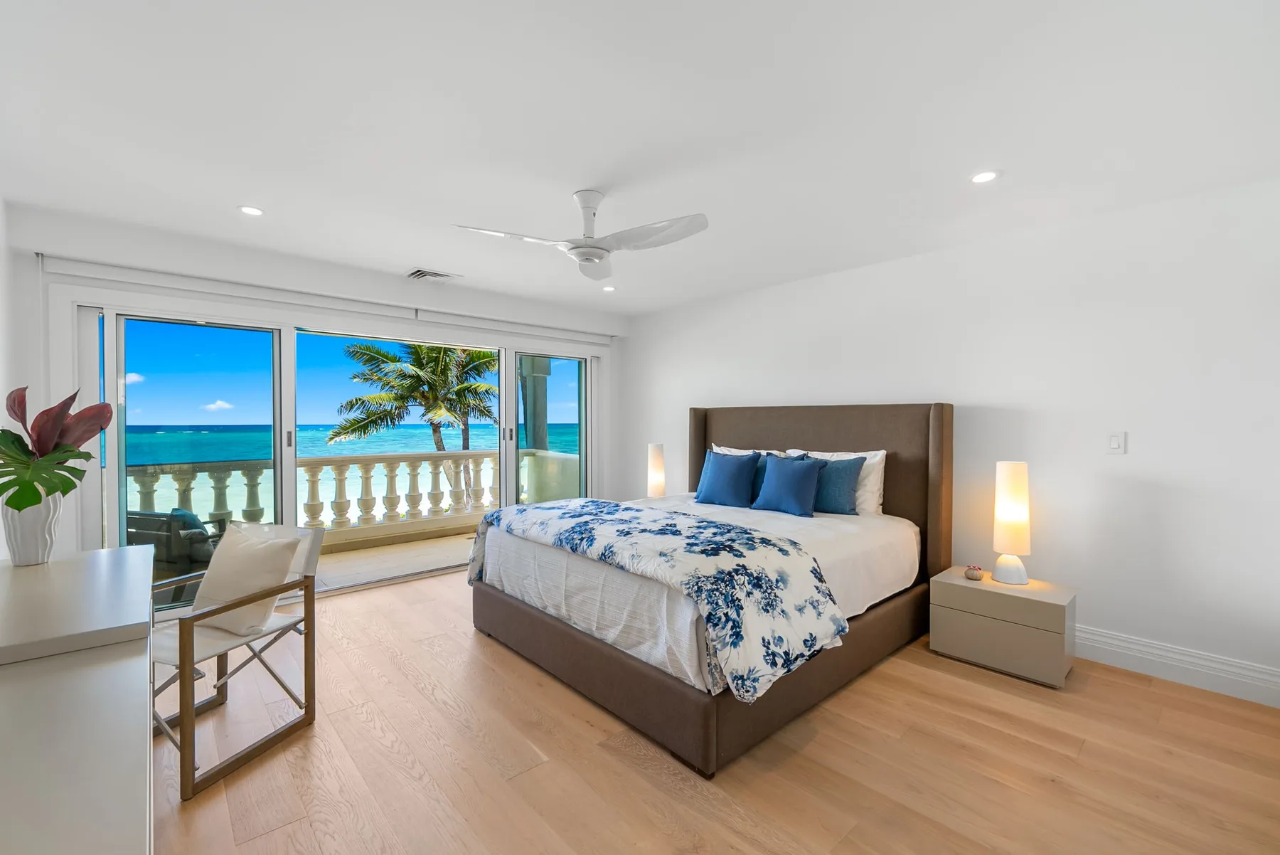 Un dormitorio luminoso con una cama junto a grandes ventanas con vistas al océano.