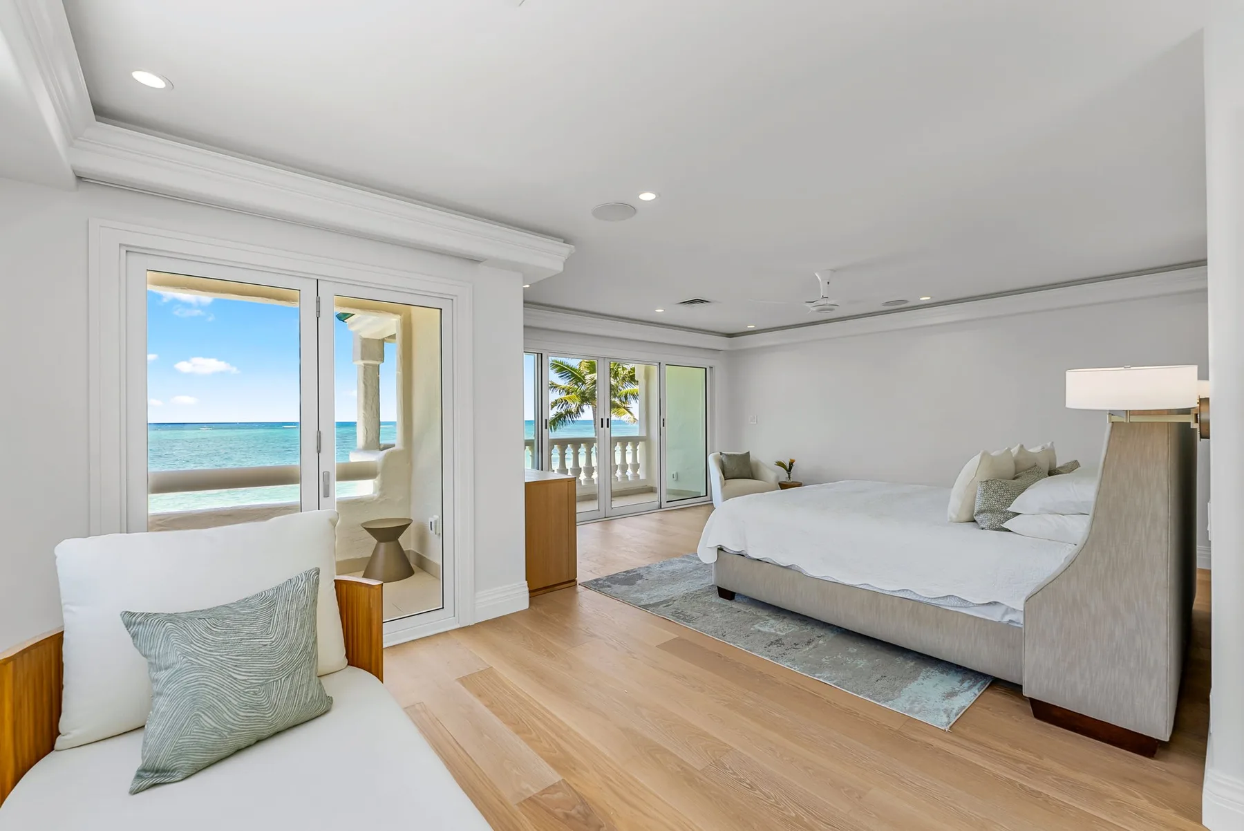 Un dormitorio luminoso con una cama grande y ventanas con vistas a la playa.