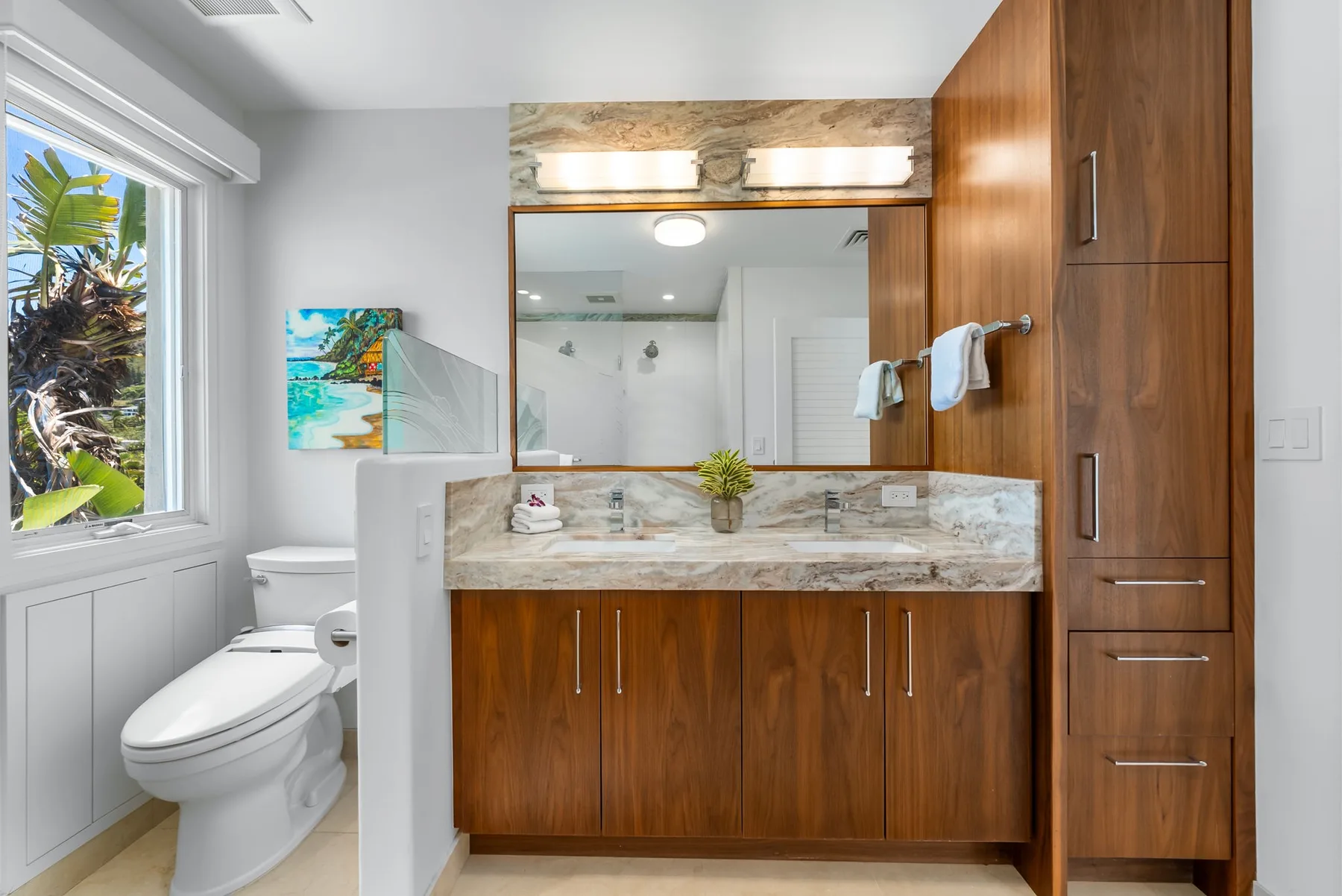 Un baño luminoso con tocador, espejo e inodoro junto a una ventana.
