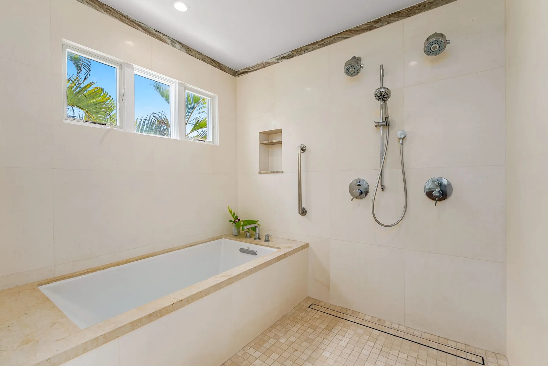 Un baño alicatado con bañera, accesorios de ducha y ventanas.