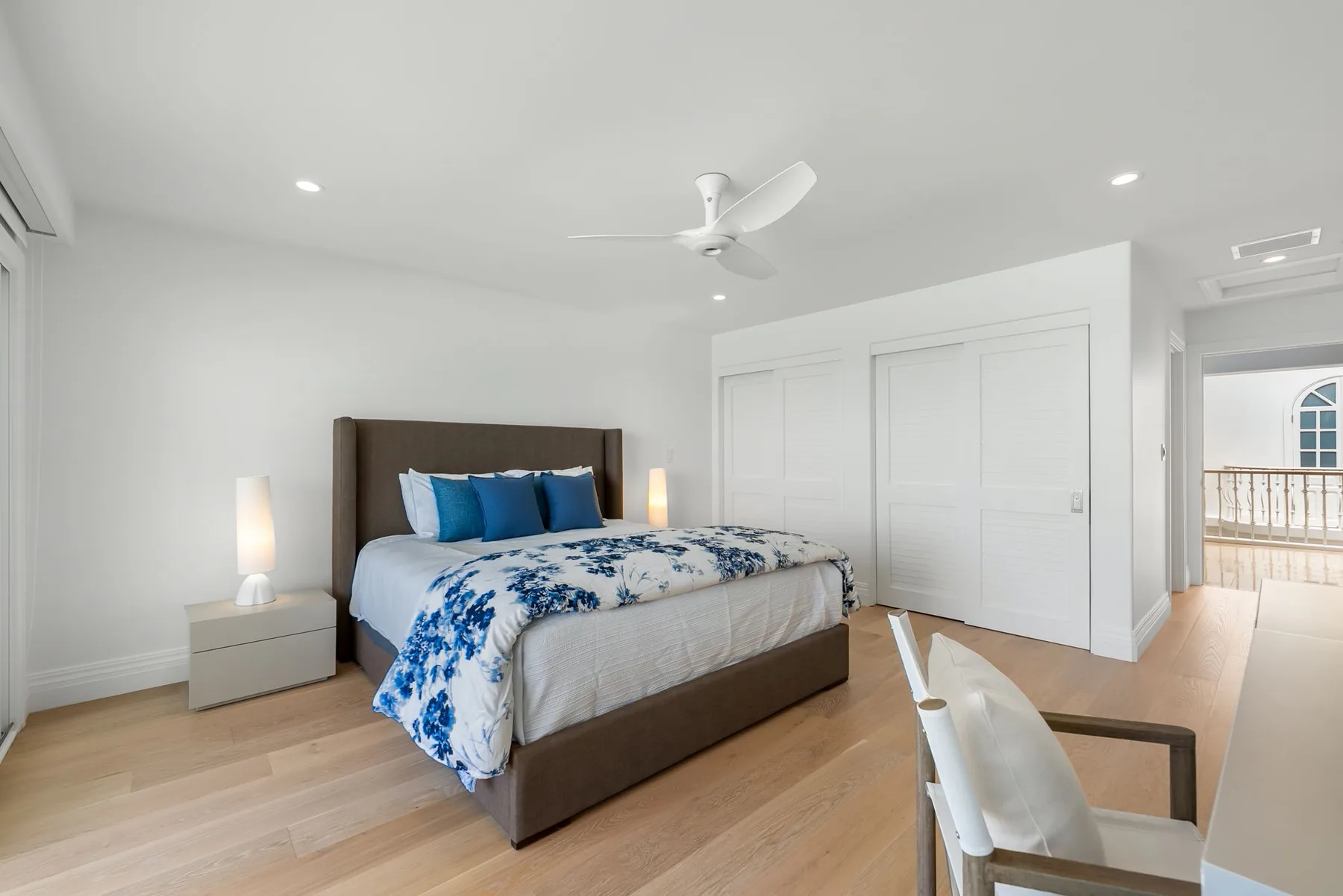 Un dormitorio luminoso con una cama y puertas blancas de armario.
