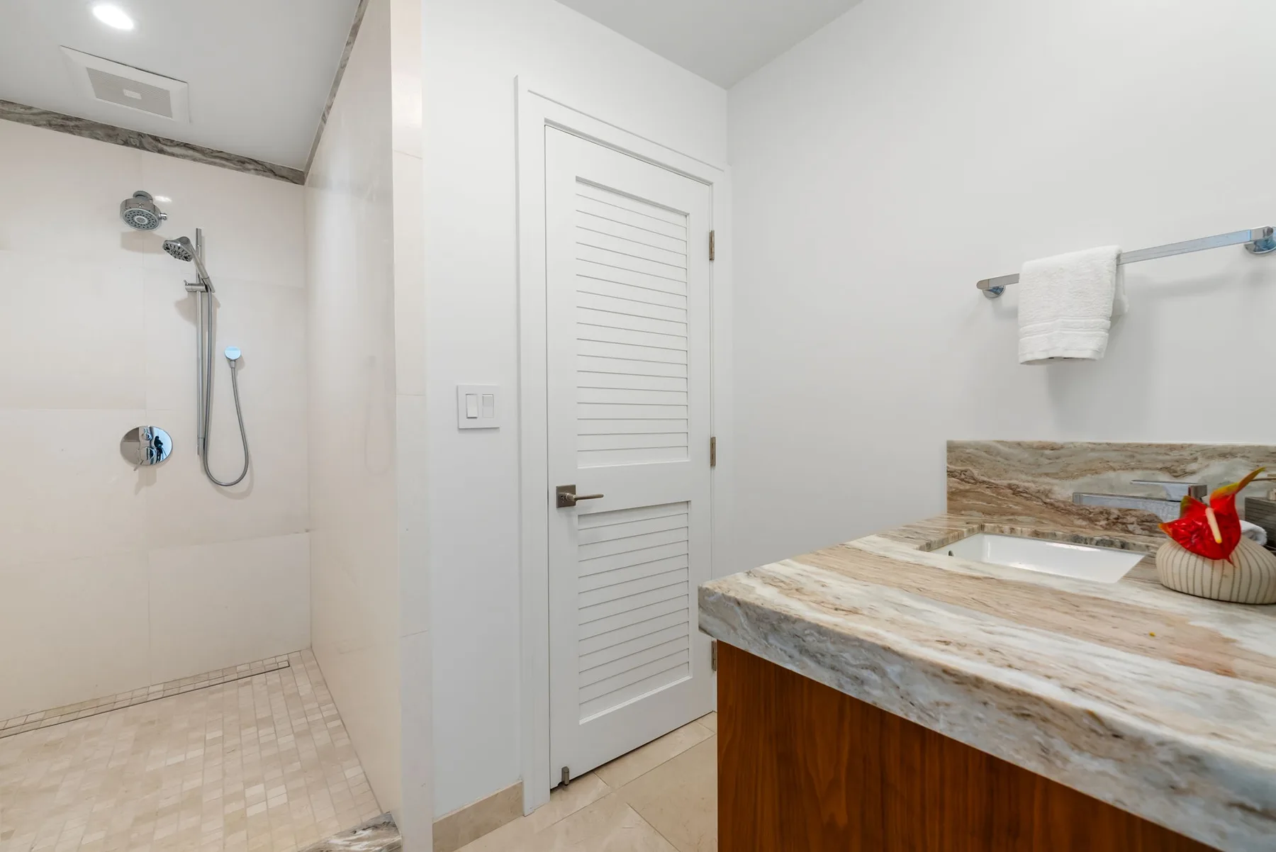 Un baño con ducha y un lavabo integrado en una encimera de aspecto pétreo.