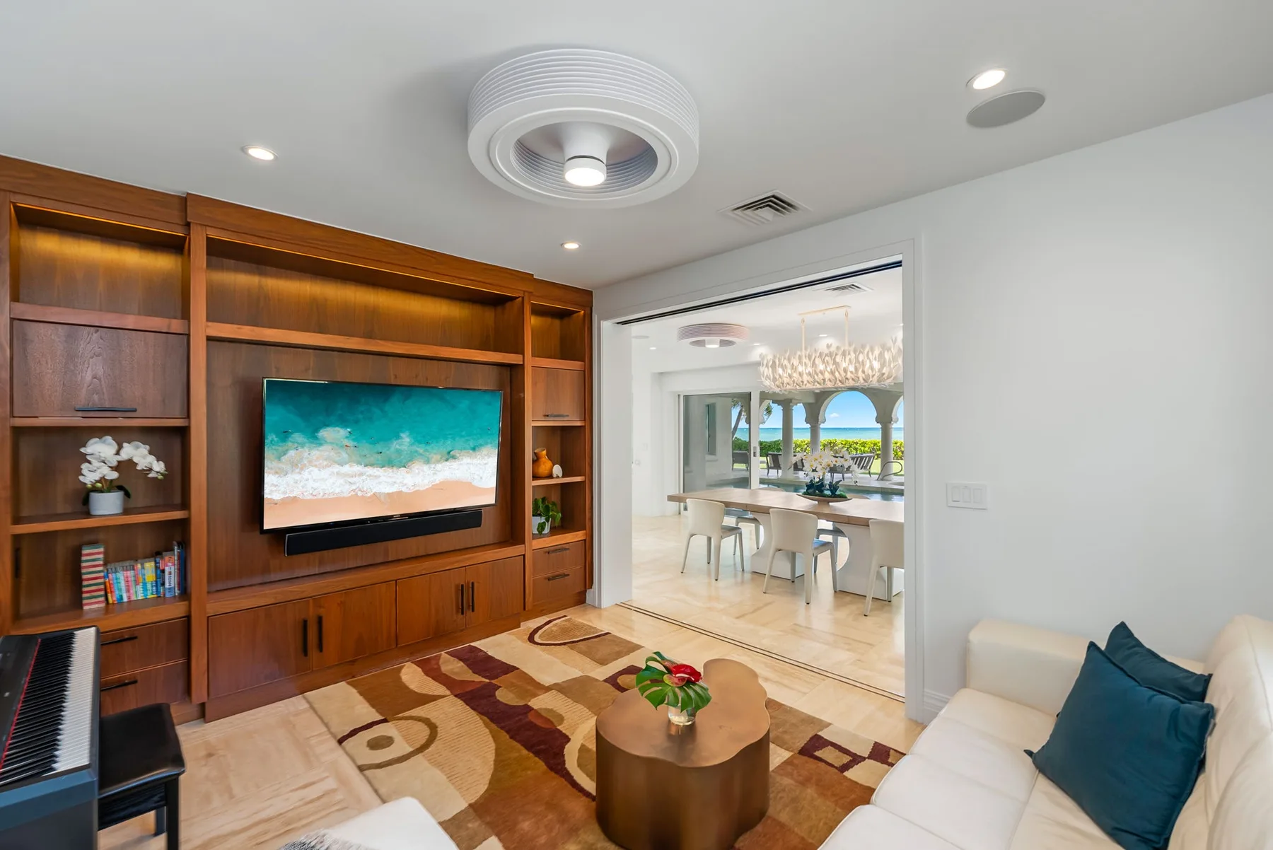 Una sala de estar con estanterías de madera y un televisor junto a un comedor.