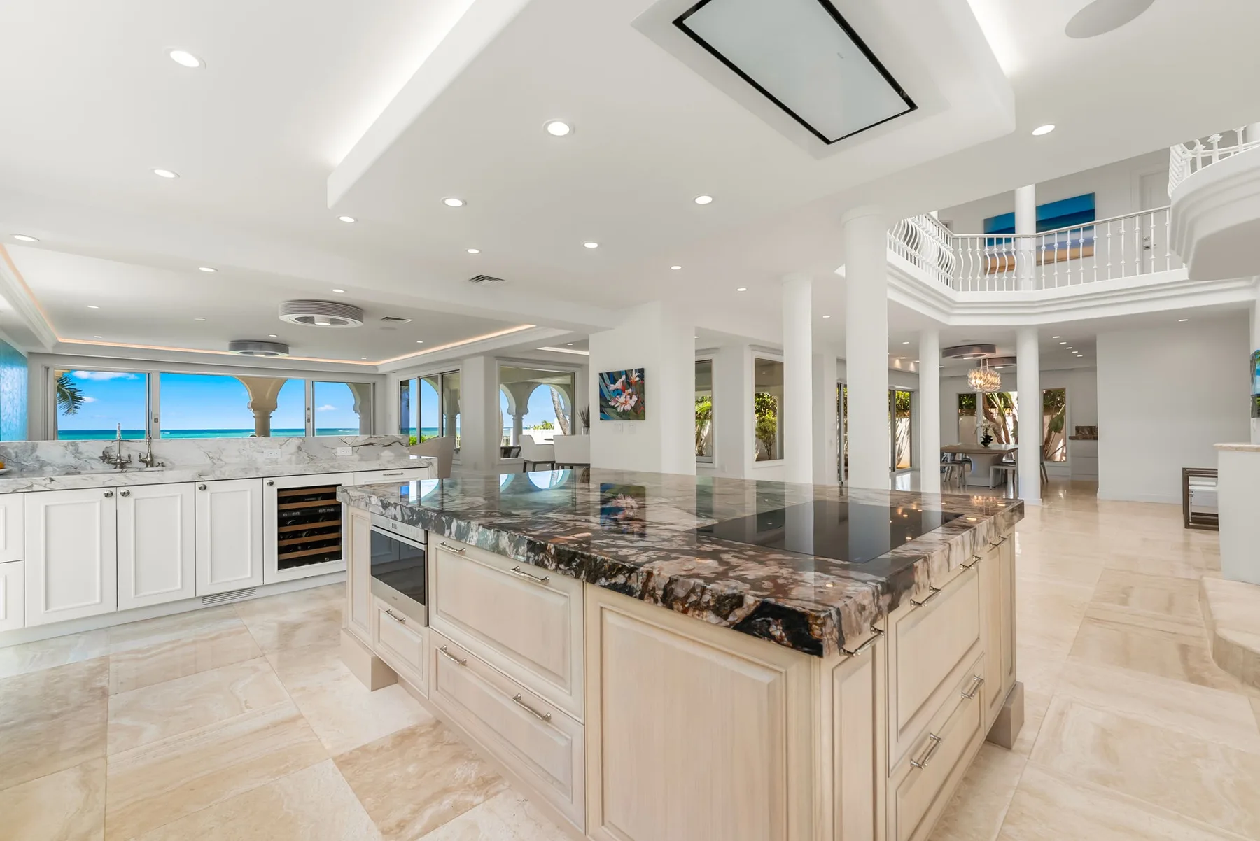 Una cocina luminosa y abierta con una gran isla central y ventanas con vistas al agua.