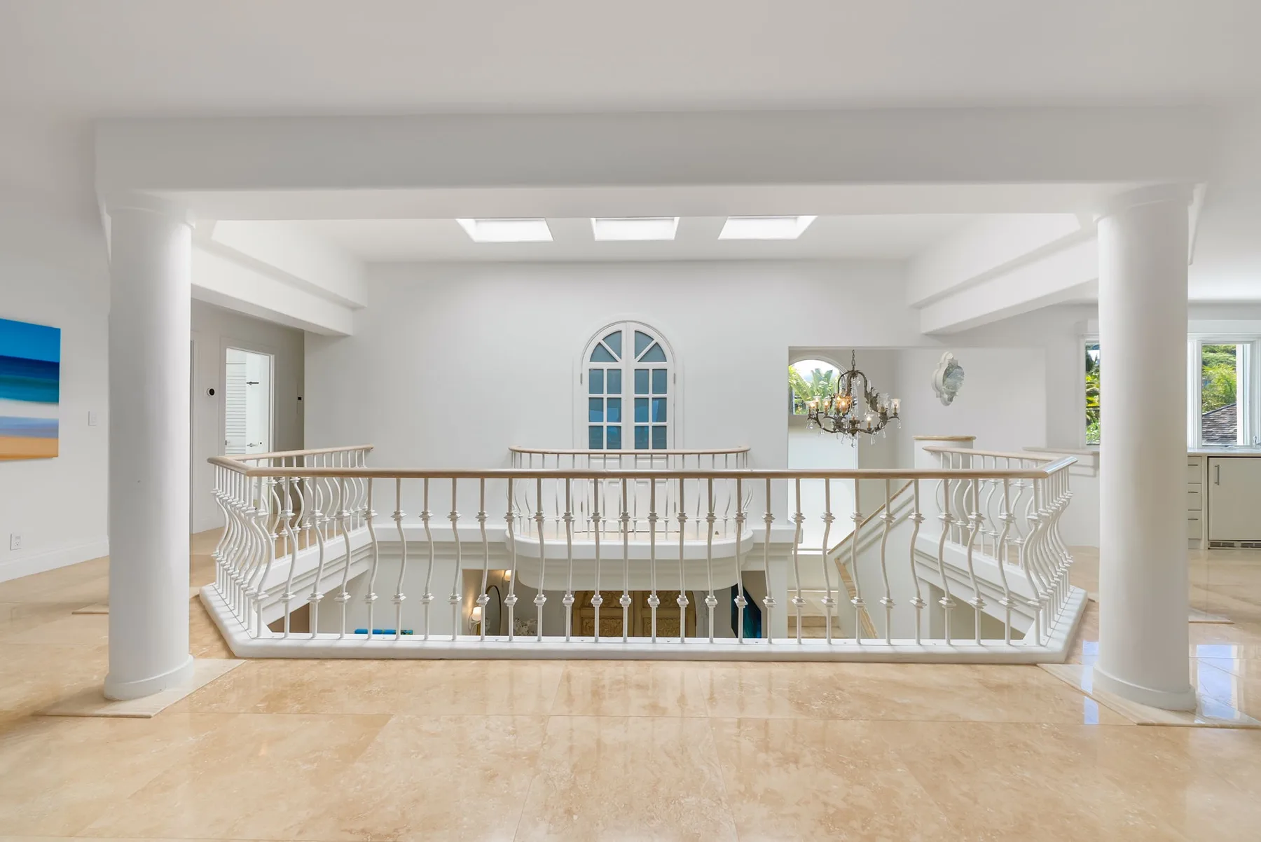 Una galería interior luminosa da a un nivel inferior tras una barandilla decorativa.