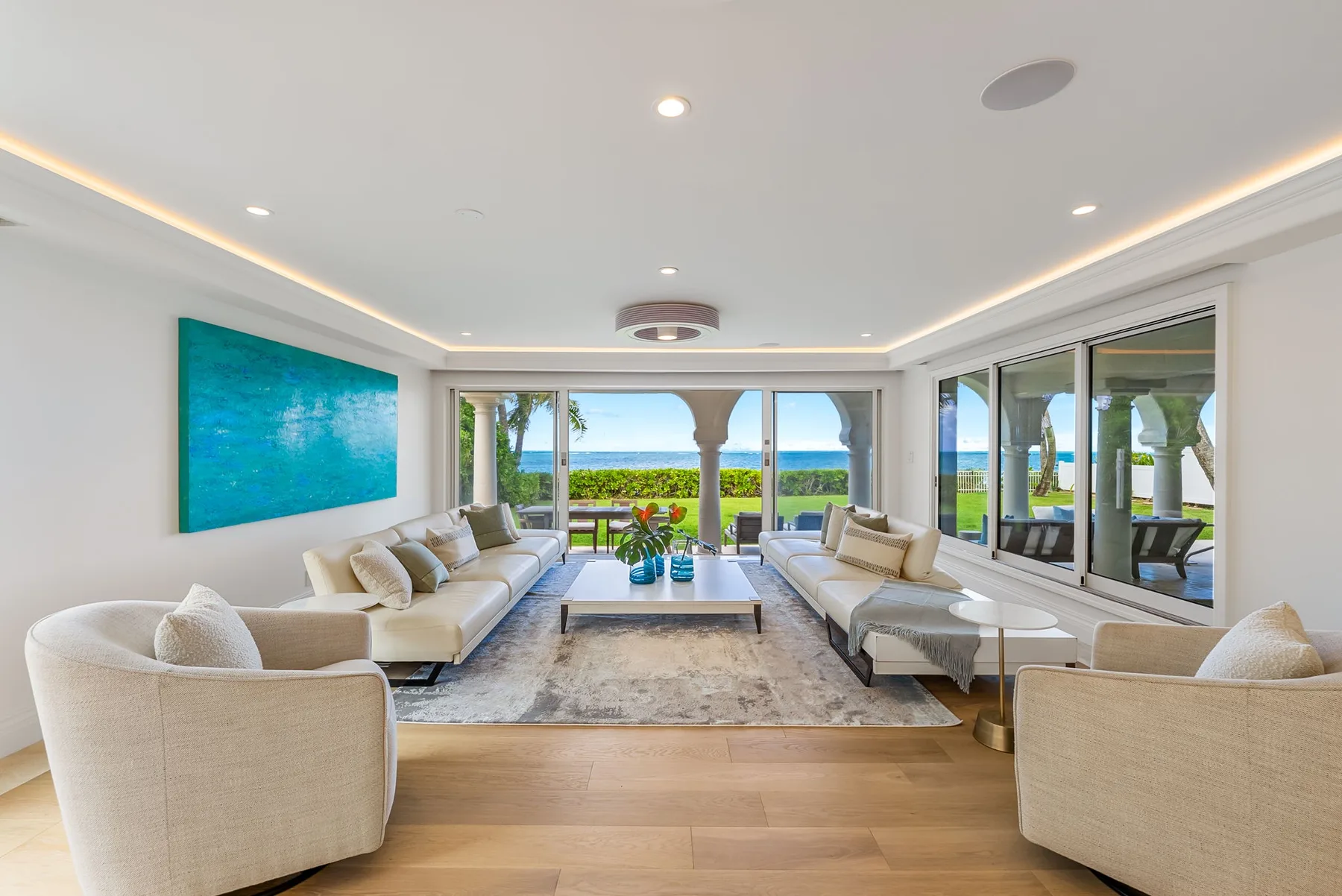 Una luminosa sala de estar con asientos alrededor de una mesa baja y vistas al mar.