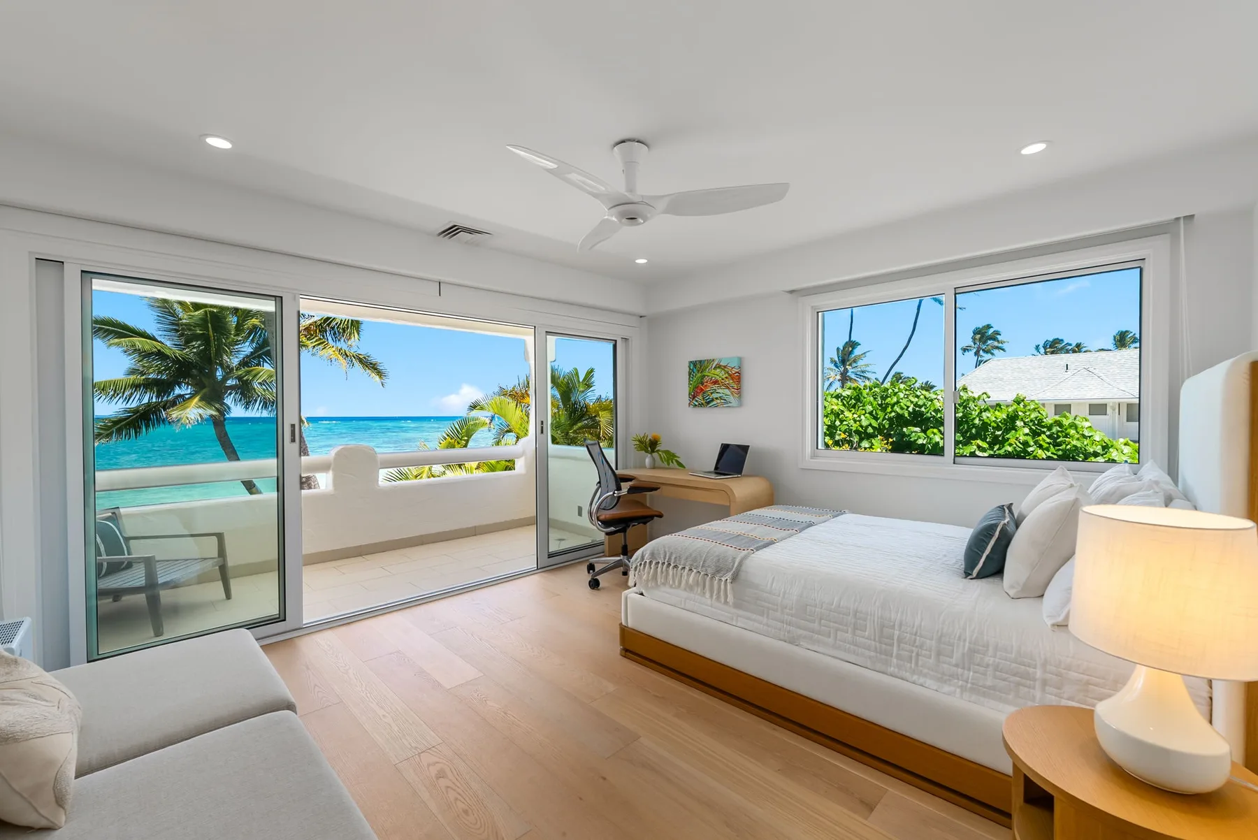 Un dormitorio luminoso con una cama y grandes ventanas con vistas al mar.