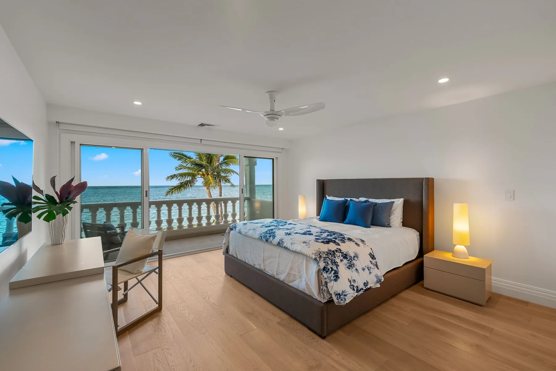 Un dormitorio con una cama junto a grandes ventanas con vista al océano.